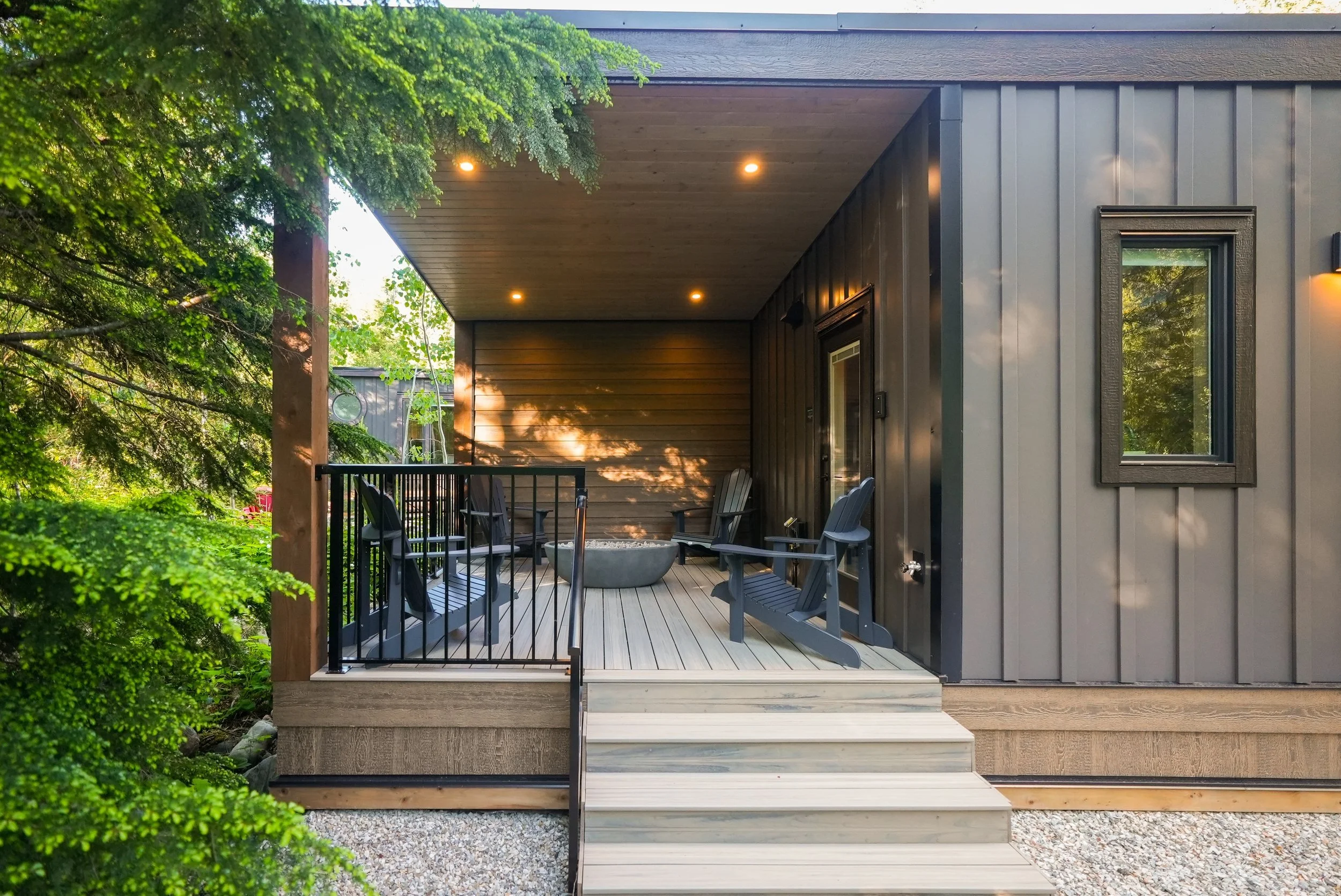 Selkirk cabin with its covered deck and steps down to the forest