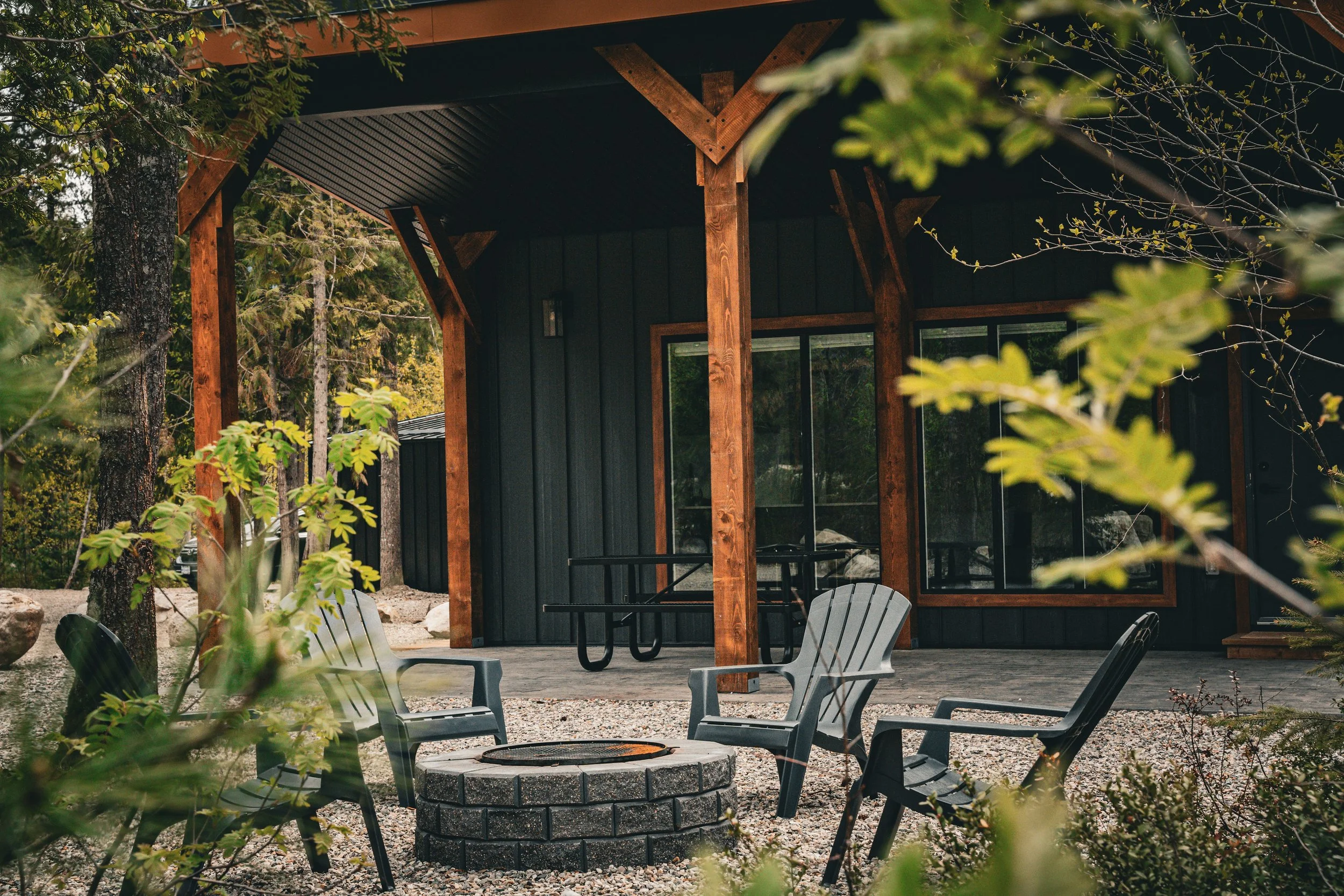 Adirondack chairs around a fire pit in front of the covered deck of the Monashee