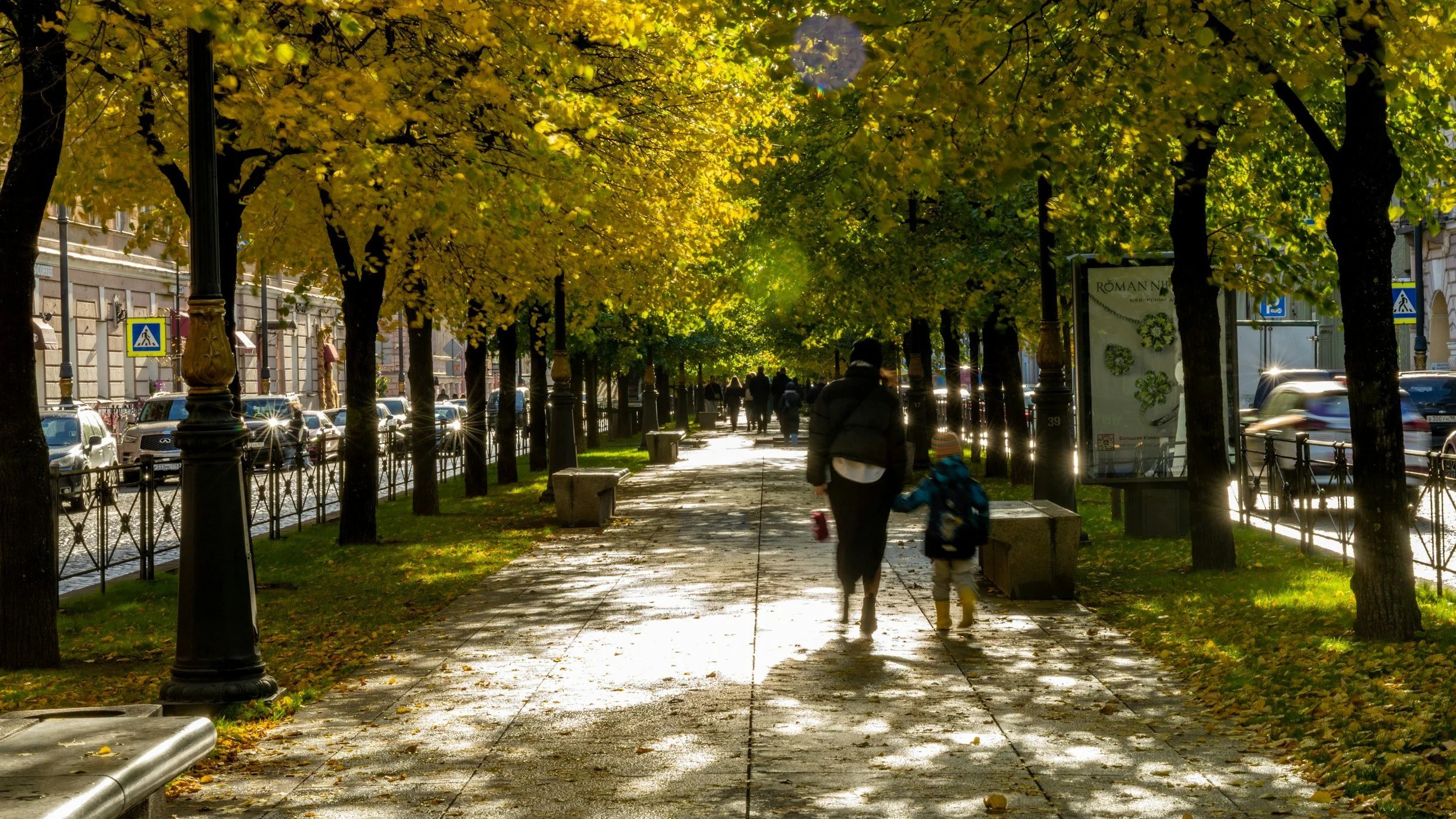 An adult and a child walking a tree-lined street on an early fall morning, the fresh start effect of September.