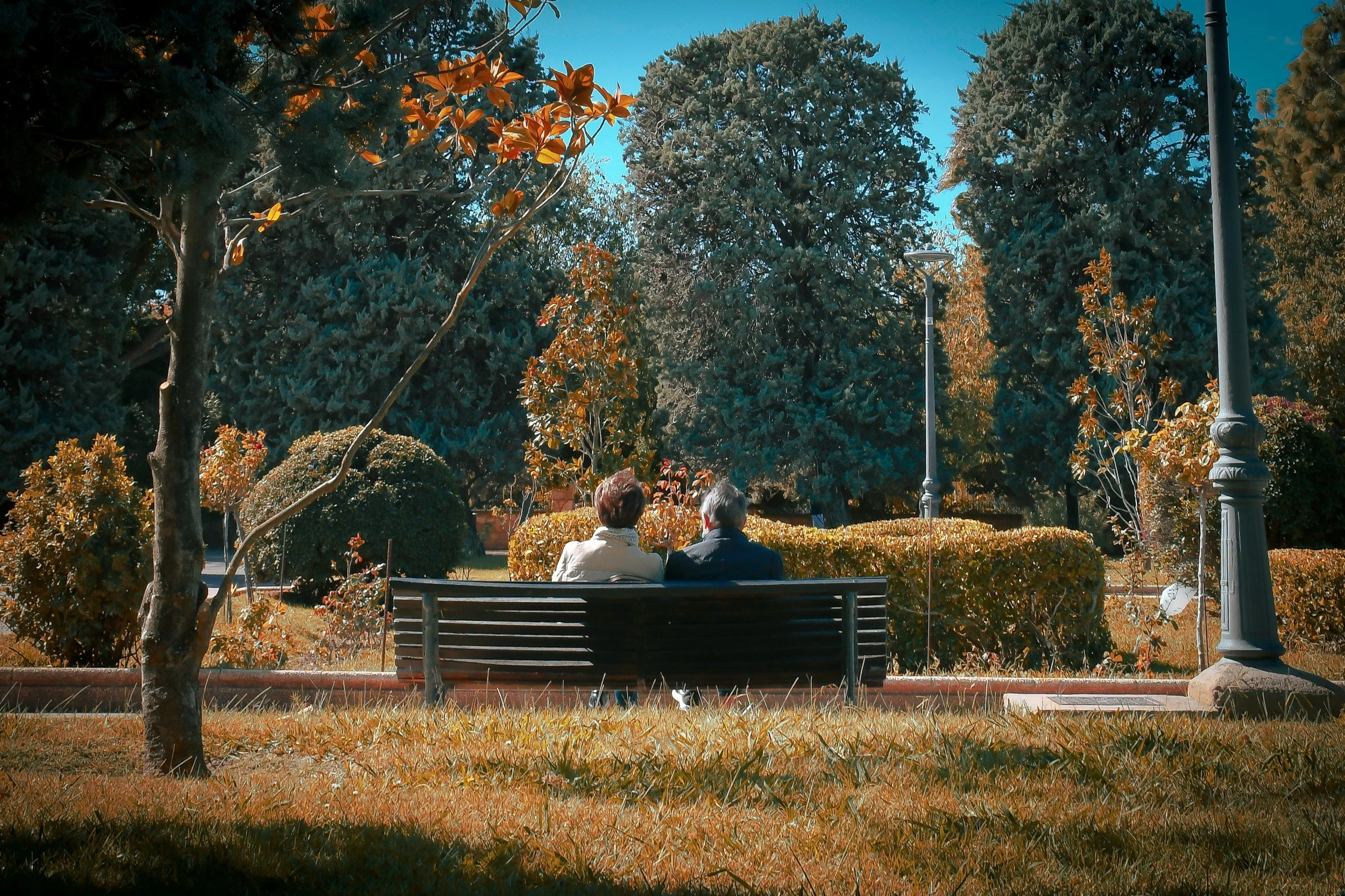 Two people sitting together quietly on a bench, one supporting someone who is struggling