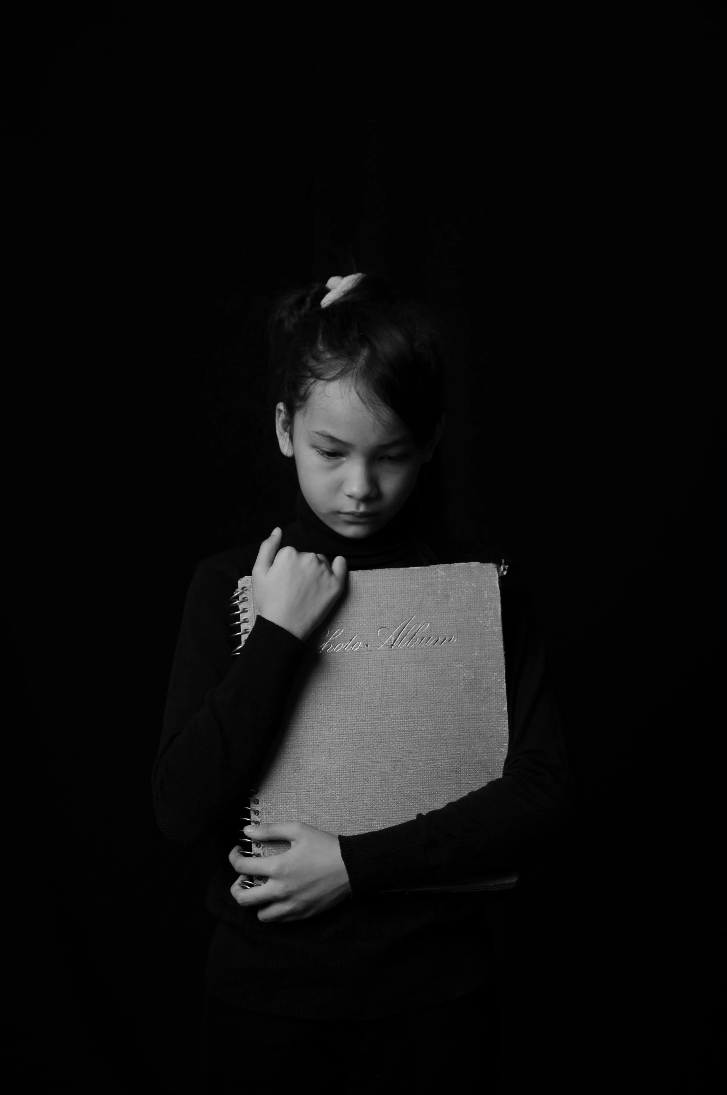 Black-and-white portrait of a sad child holding a notebook, symbolizing inner child healing, childhood wounds, and reparenting work in therapy.