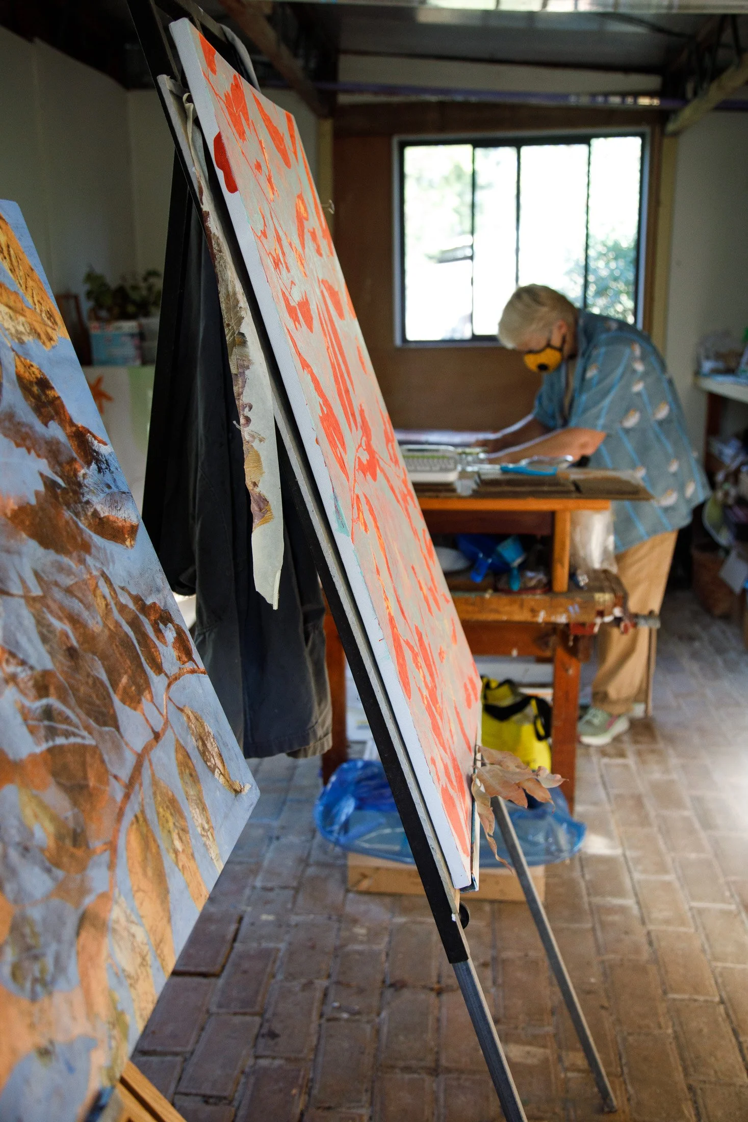 Artist at work inside a home studio surrounded by large-scale paintings and creative materials during a documentary-style Maker Series session, Mornington Peninsula