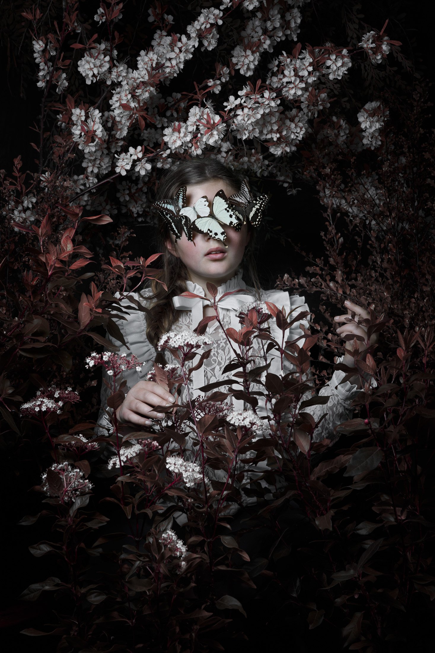 Fine art portrait of a young girl surrounded by flowering branches and butterflies, exploring themes of nature, transformation and identity