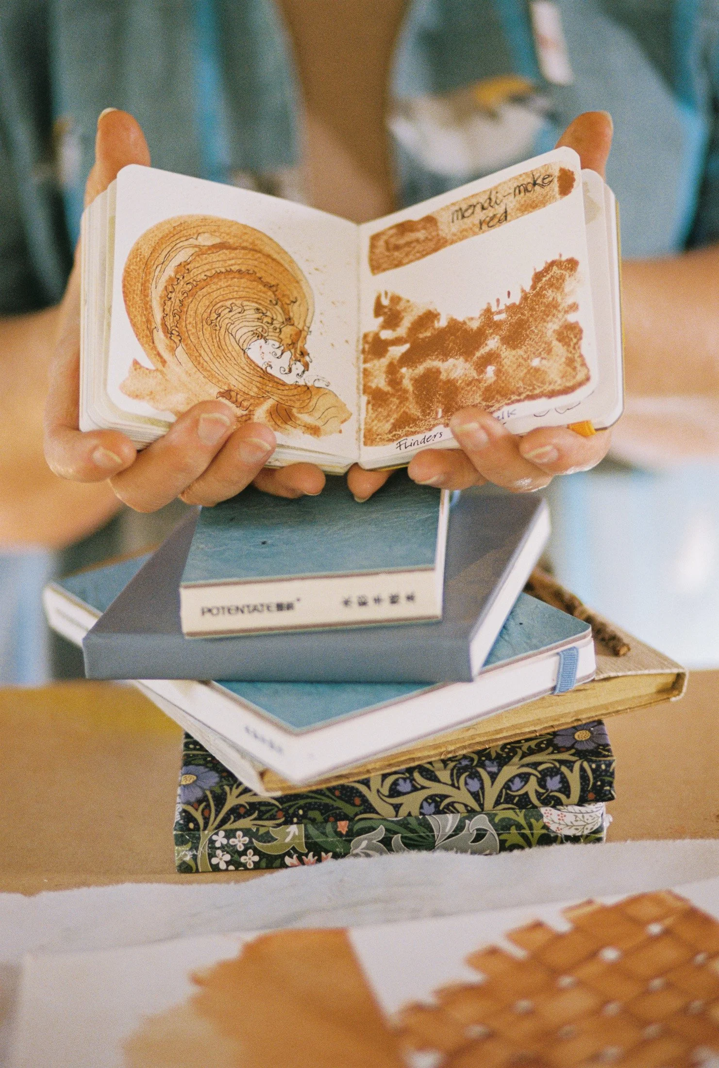 Close-up of an artist holding handmade sketchbooks and creative studies during a Maker Series portrait and studio documentation session in Mornington Peninsula
