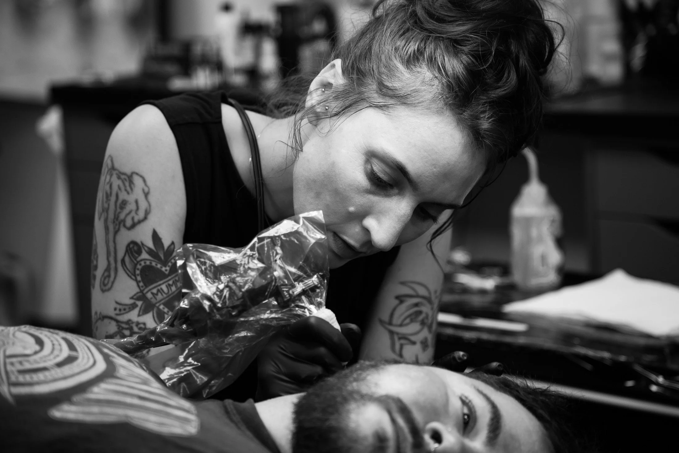 Tattoo artist concentrating during a live tattoo session captured in natural documentary style portrait photography.