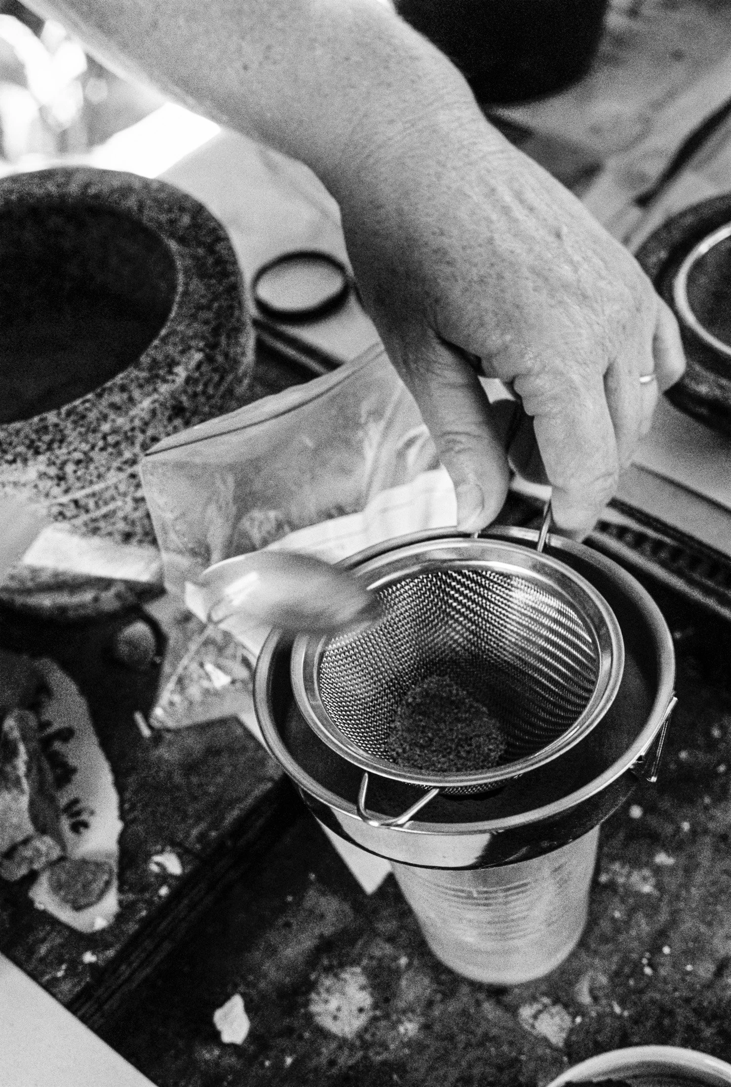 Black and white detail photograph of hands preparing materials during an artist process and maker session.