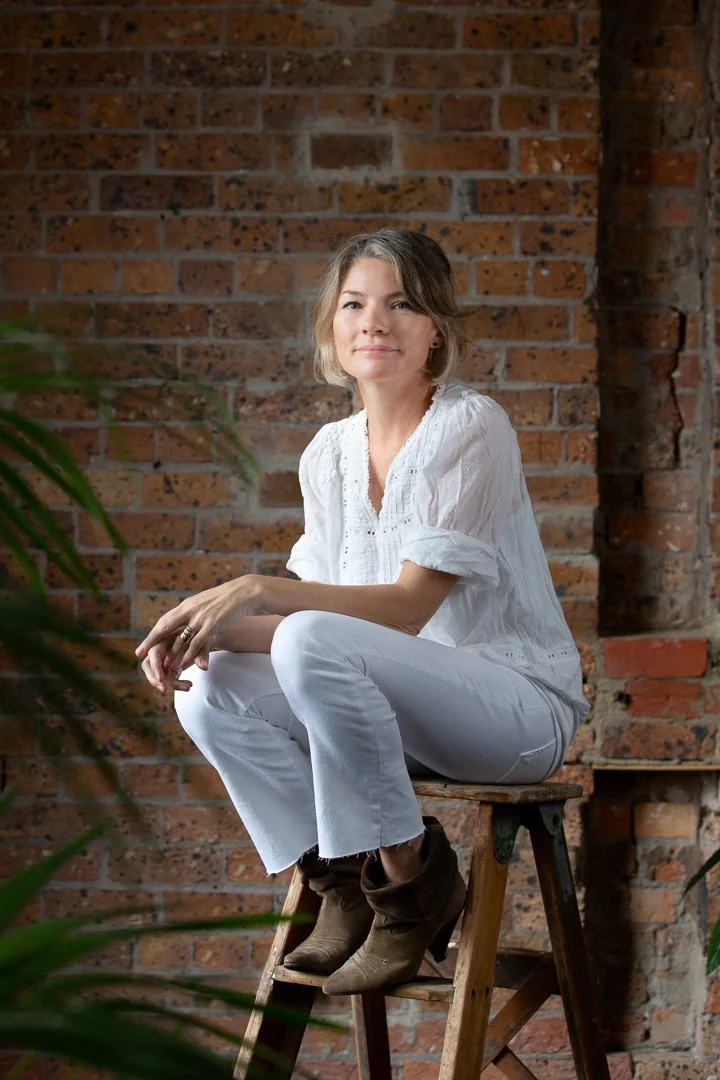 Urban feel headshot portrait of a young woman with brick wall background by Natalie Finney Photography