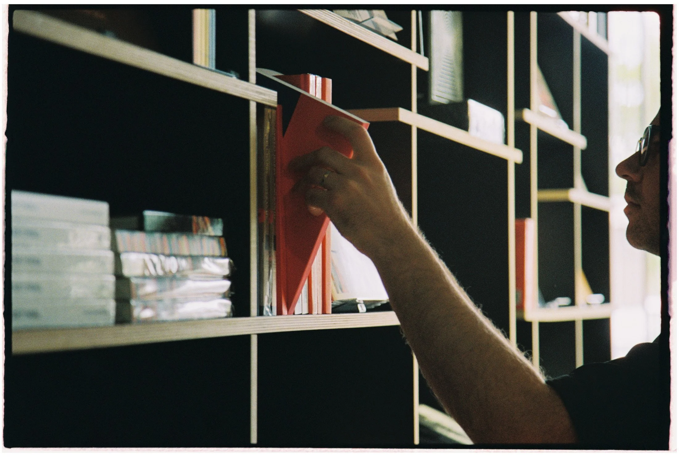 Artist interacting with bookshelves and studio displays during a creative workspace documentation session.