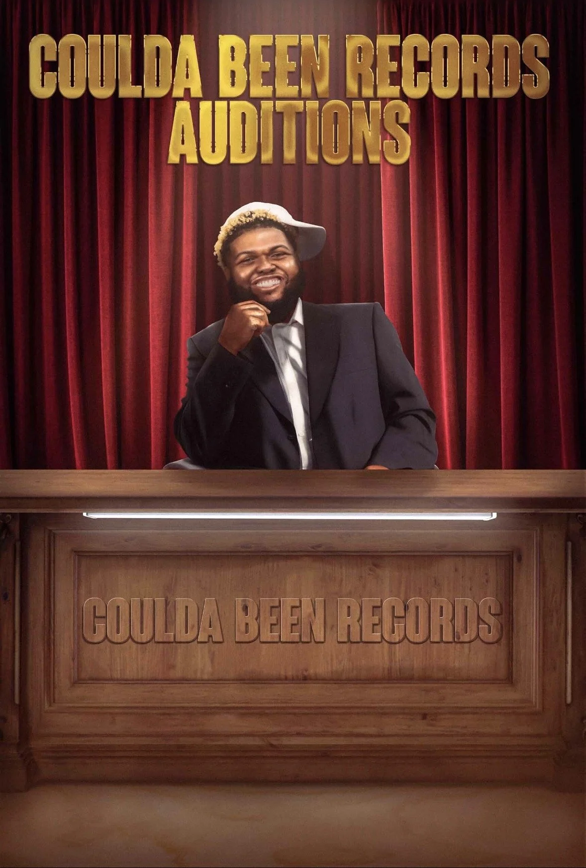 Man with a beard, smiling, dressed in a suit, wearing a white cap backwards, sitting behind a wooden desk in front of a red curtain backdrop with gold text reading 'Coulda Been Records Auditions'.
