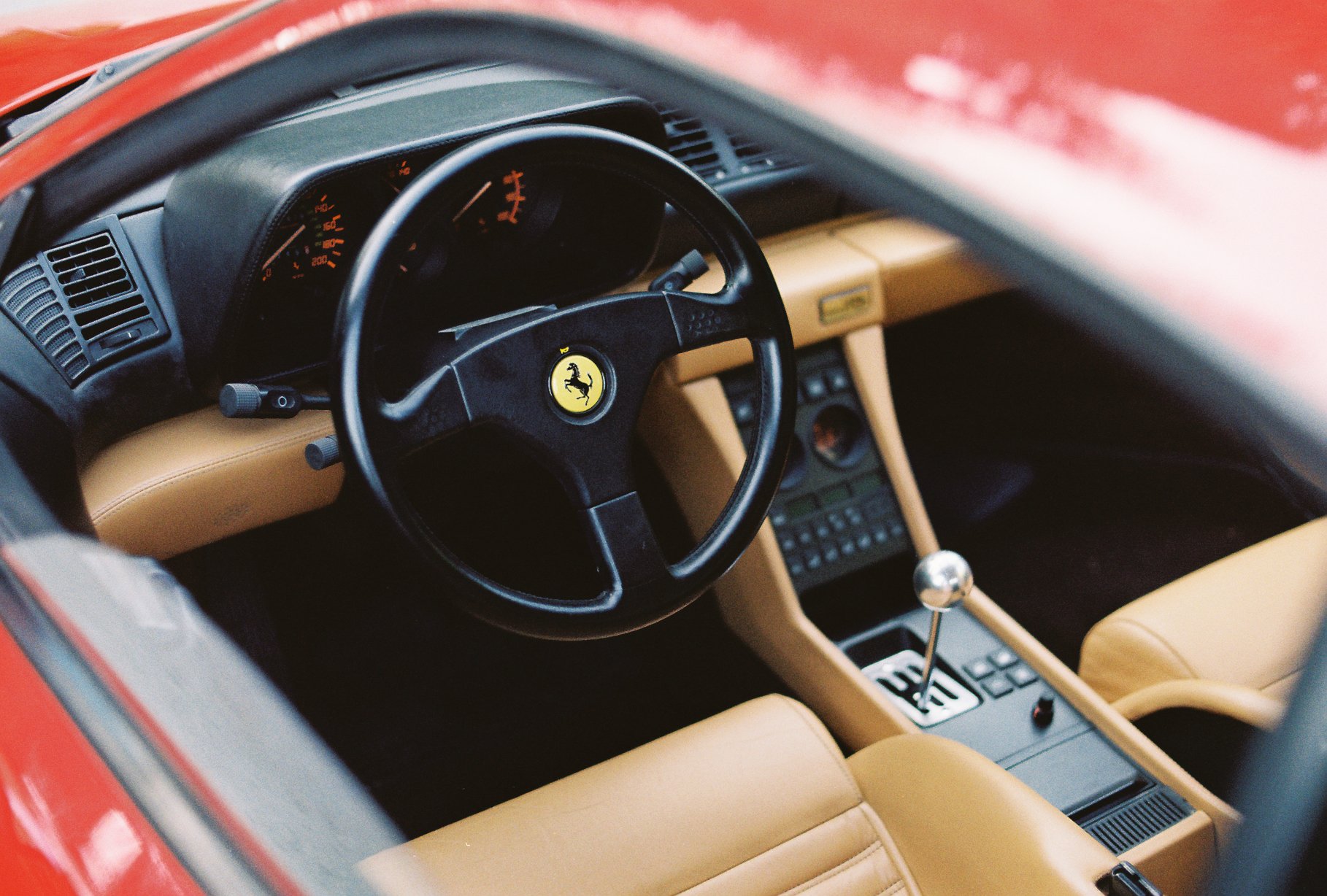 View into the Ferrari 348’s tan leather cabin, showing its steering wheel and centre console on Kodacolor 200 film.