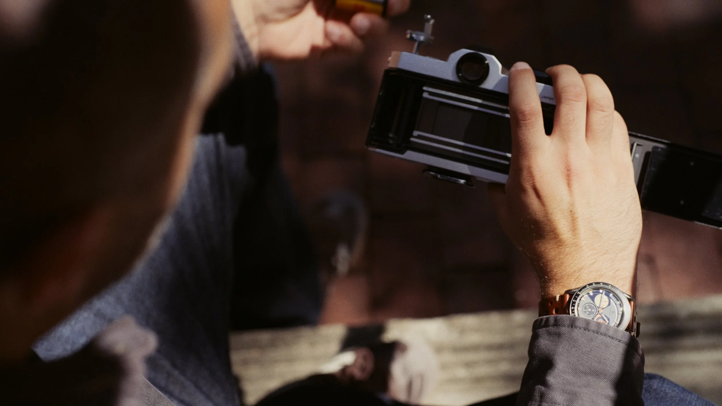 Video frame of Nima inspecting the open back of a Nikomat film camera while wearing the Nezumi Voiture VM2.