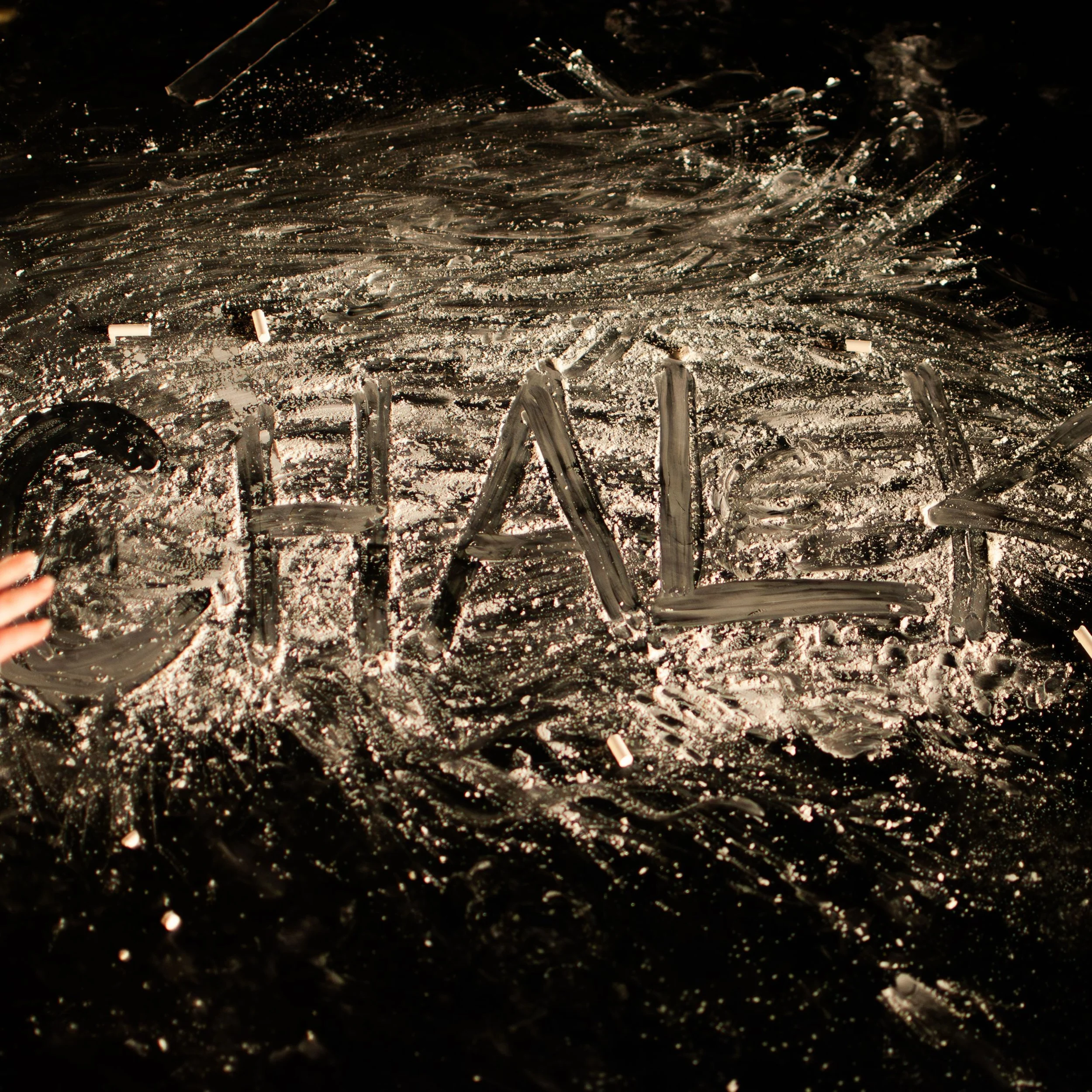 The word 'CHAL' written with finger on a foggy, dusty black surface.