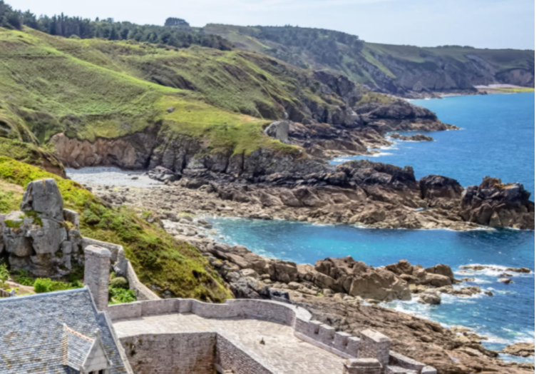 Pays Basque - A coastal landscape with rocky cliffs, a small sandy beach, and green hills overlooking the ocean.