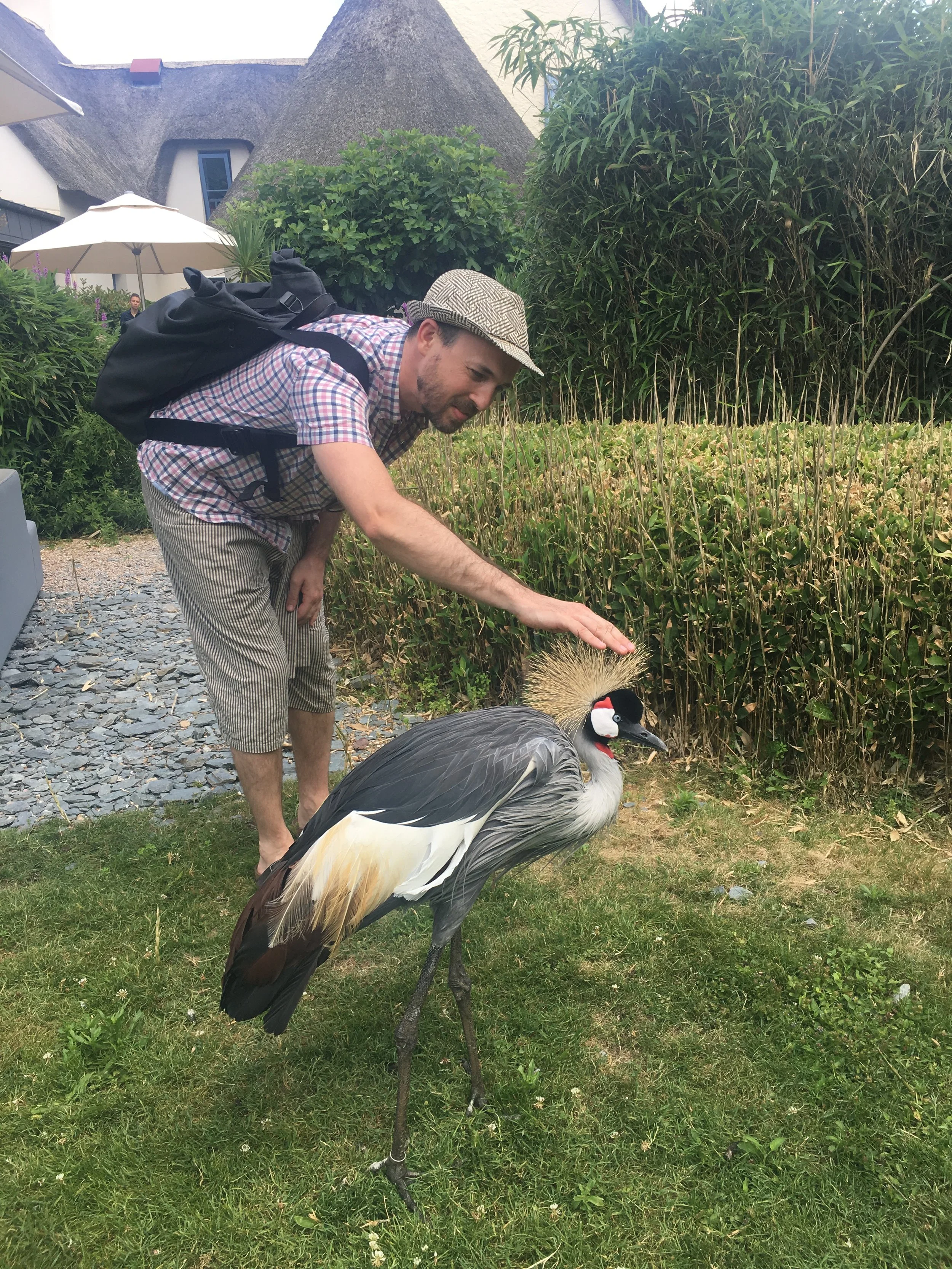Two men smiling and standing together in front of a black and white abstract mural with bold, thick lines and stylized leaf shapes.