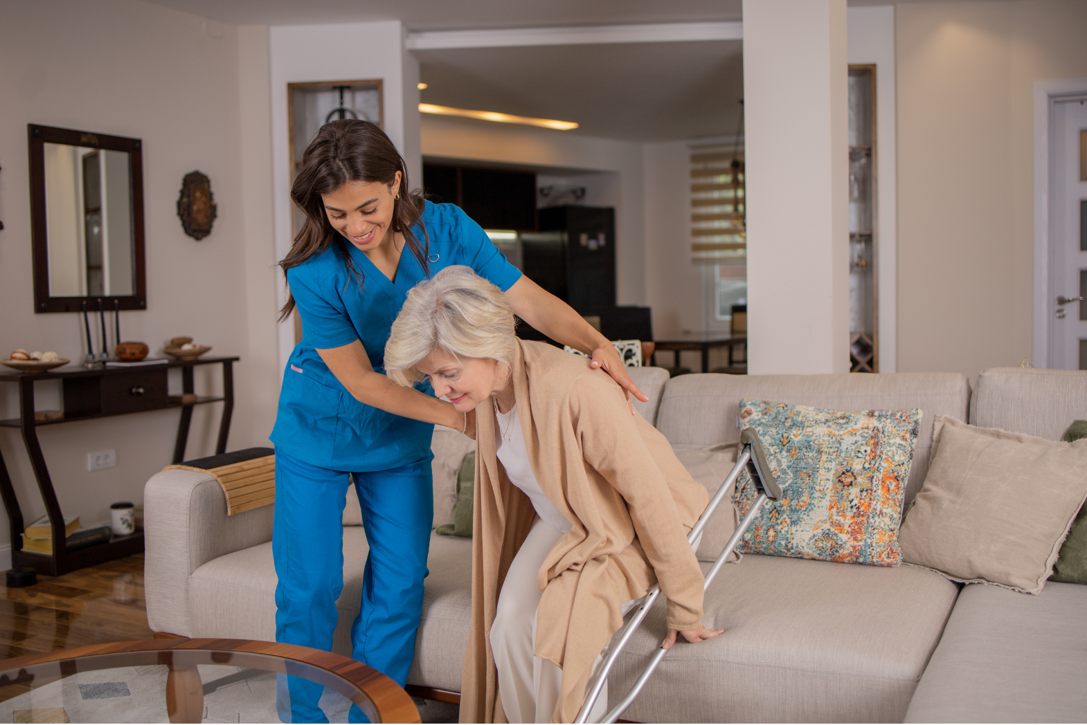 smiling carer assisting an elderly lady getting off the sofa and mobility support - re-vite