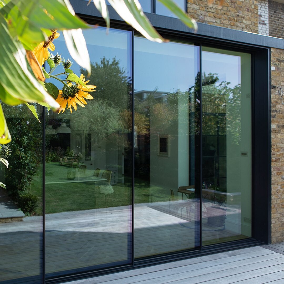 Super sized sliding doors give an industrial edge to this elegant home in South Woodford. Loving the sunflowers peeping through - bring on summer 2021! #humbleandhumble⁠⁠