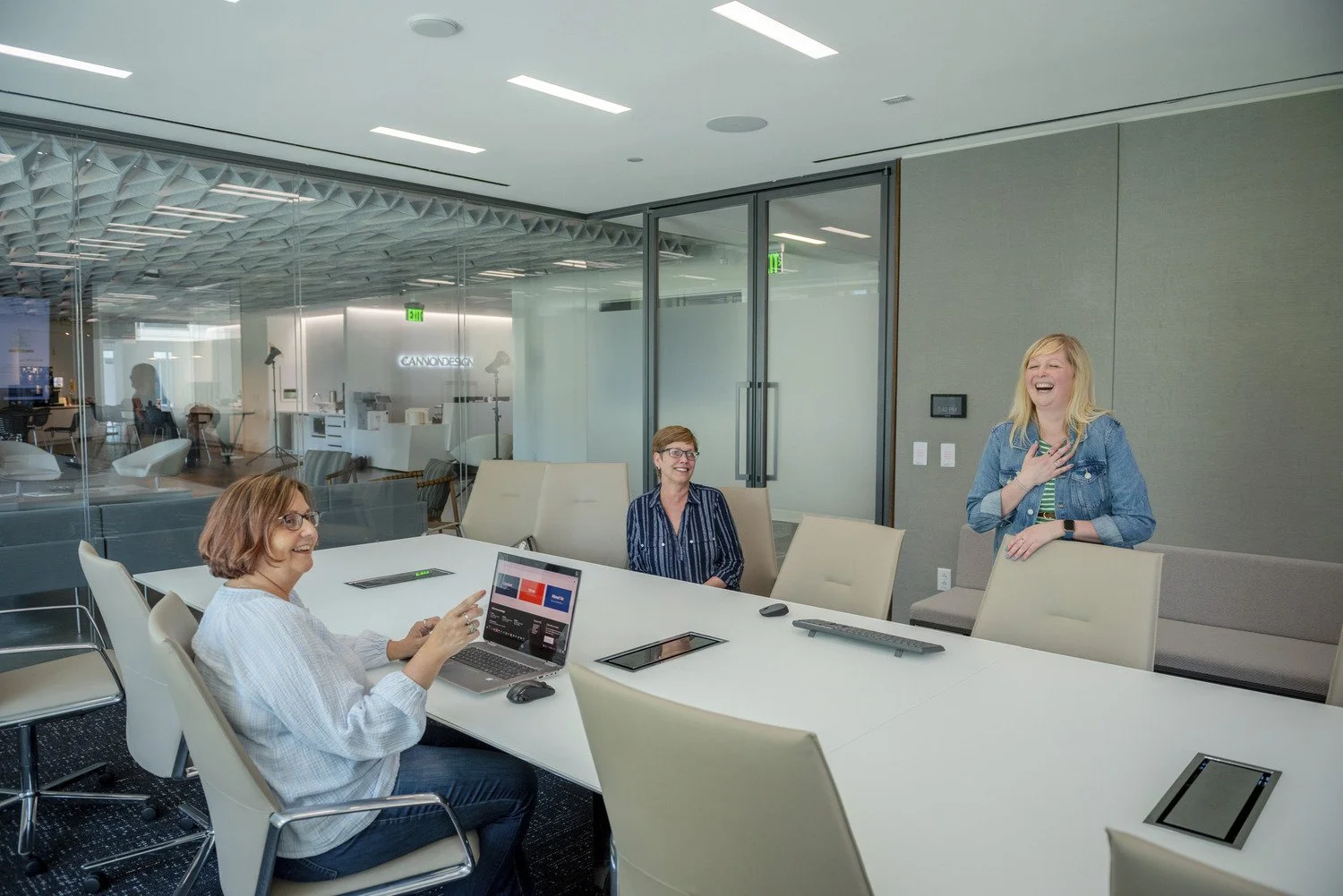 Cindy Ruggerio, Kathy Rieger, Darra Kubera laugh around conference table