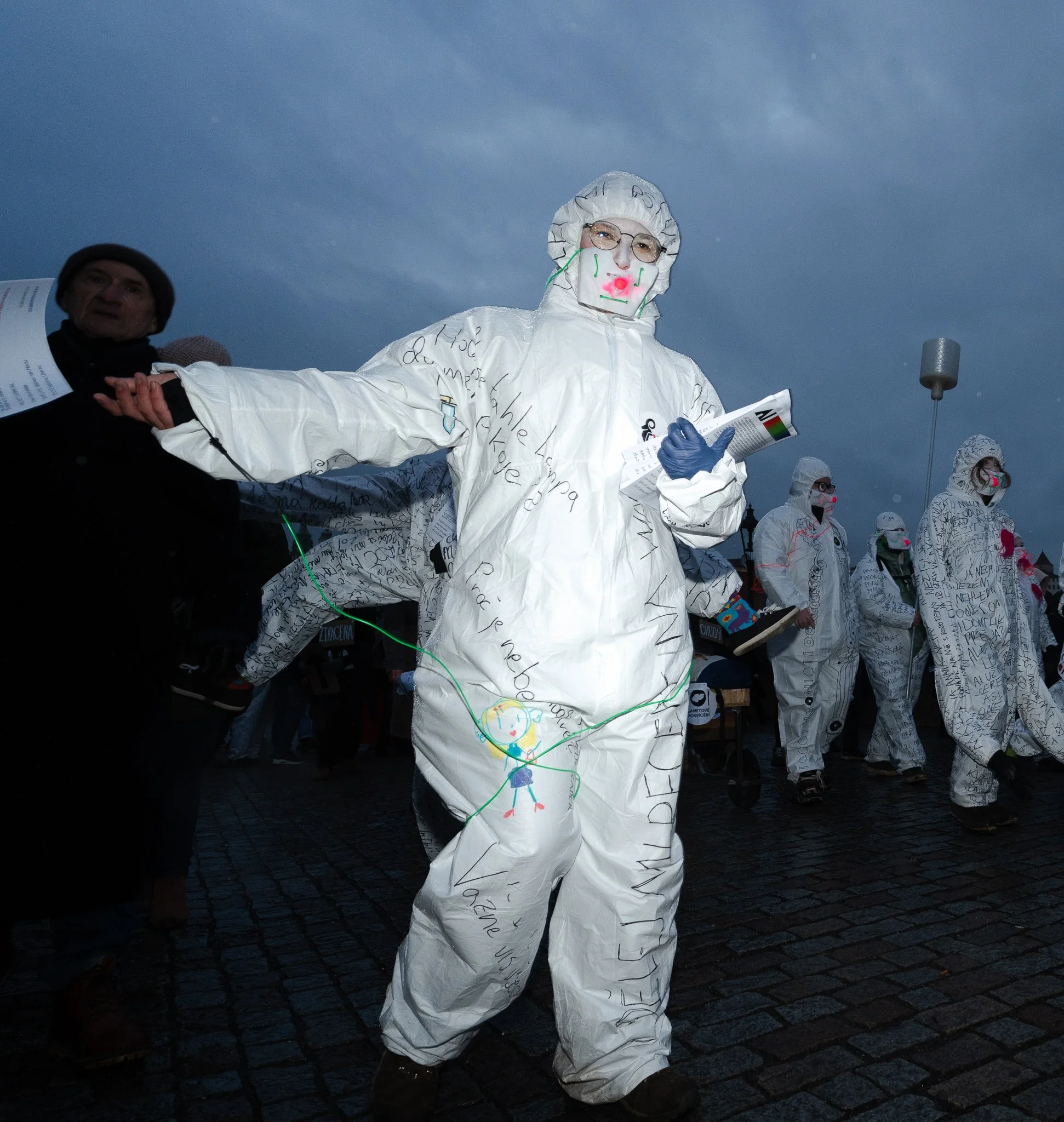 A protester marches across Charles Bridge, wearing a hazmat suit intended to represent the toxicity of AI in society.