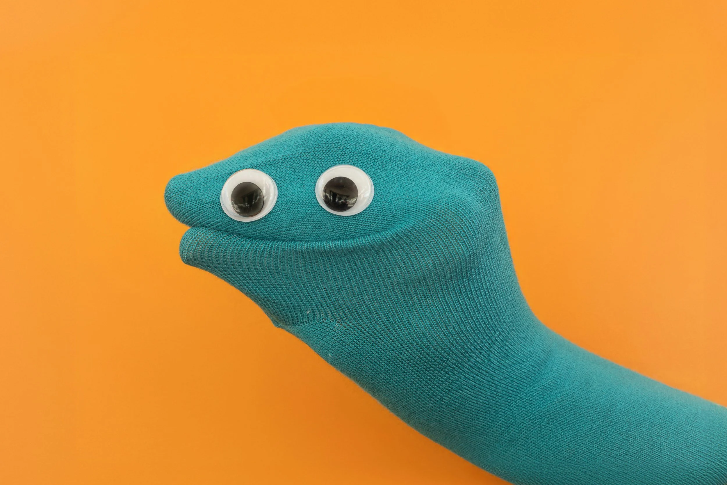 Yellow background with teal sock puppet