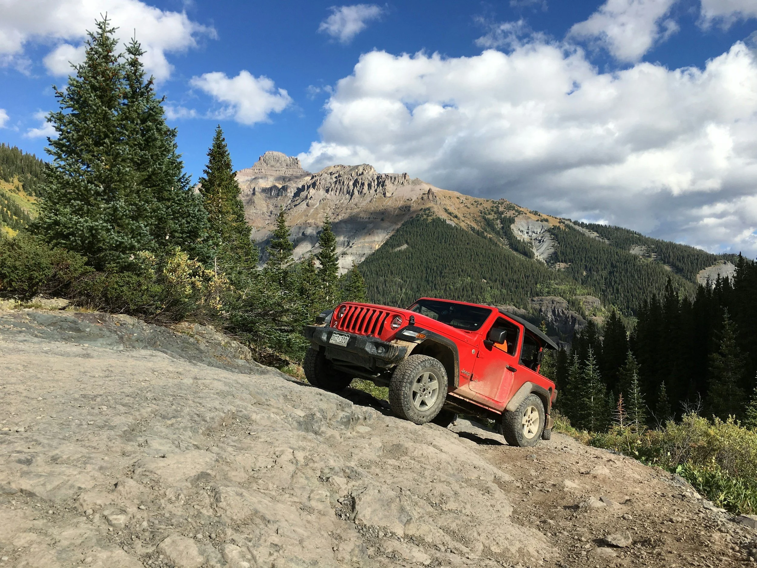Red Jeep off-roading on rocky terrain