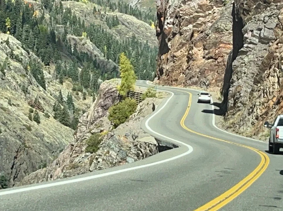 Vehicles traveling along a steep cliffside section of the Million Dollar Highway in the San Juan Mountains of Colorado