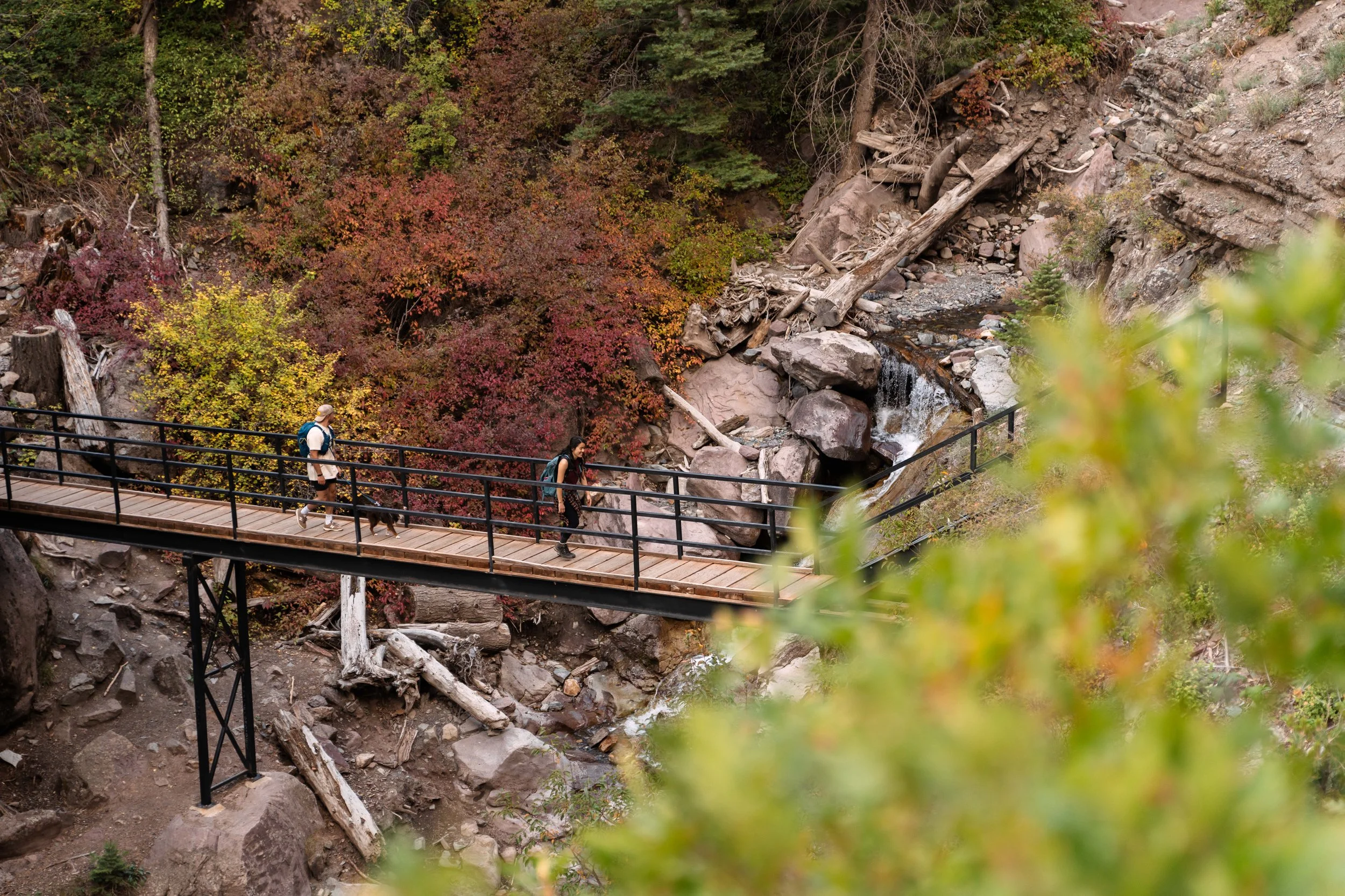 Two hikers crossing pedestrian hiking bridge