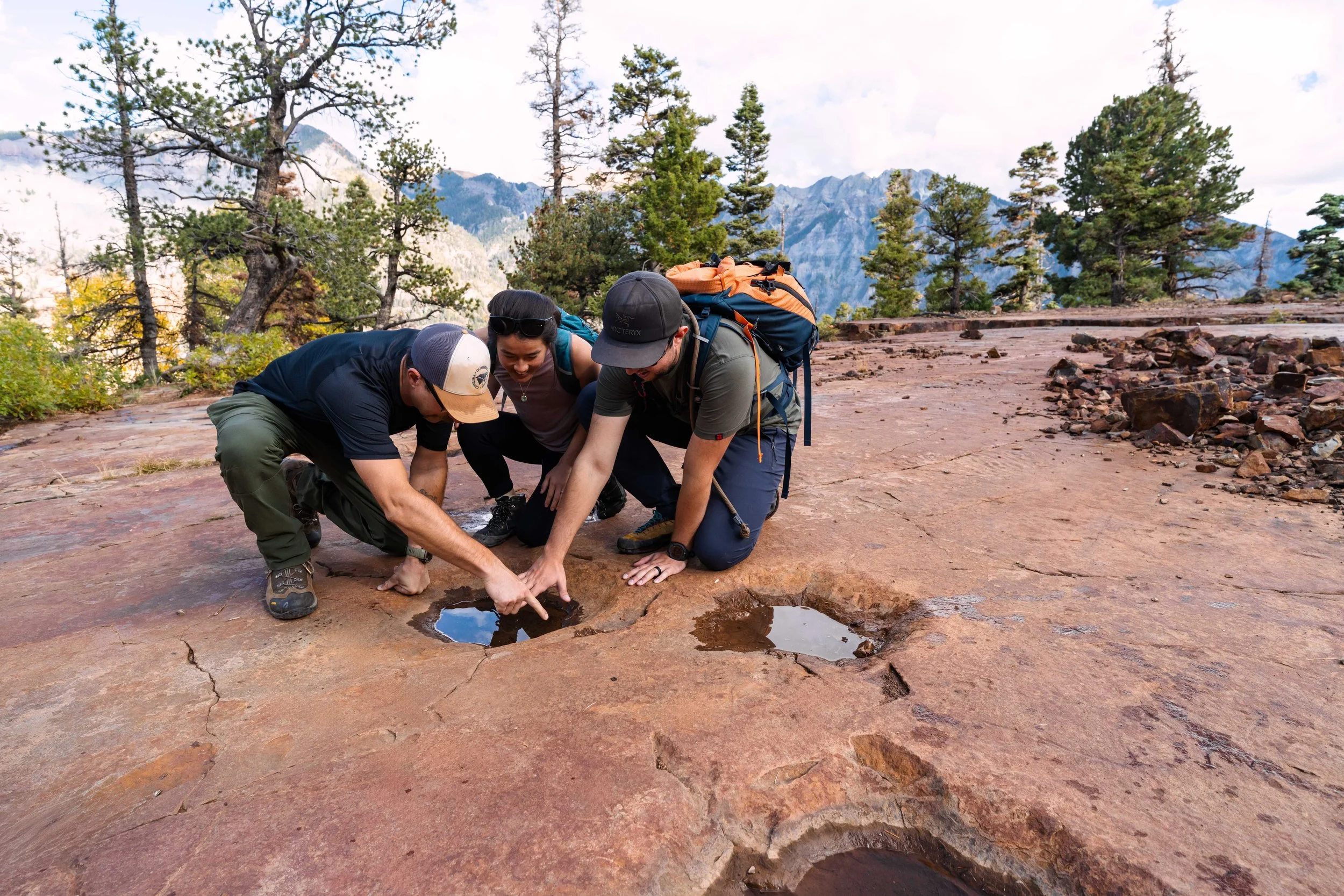 3 people crouch at dino tracks