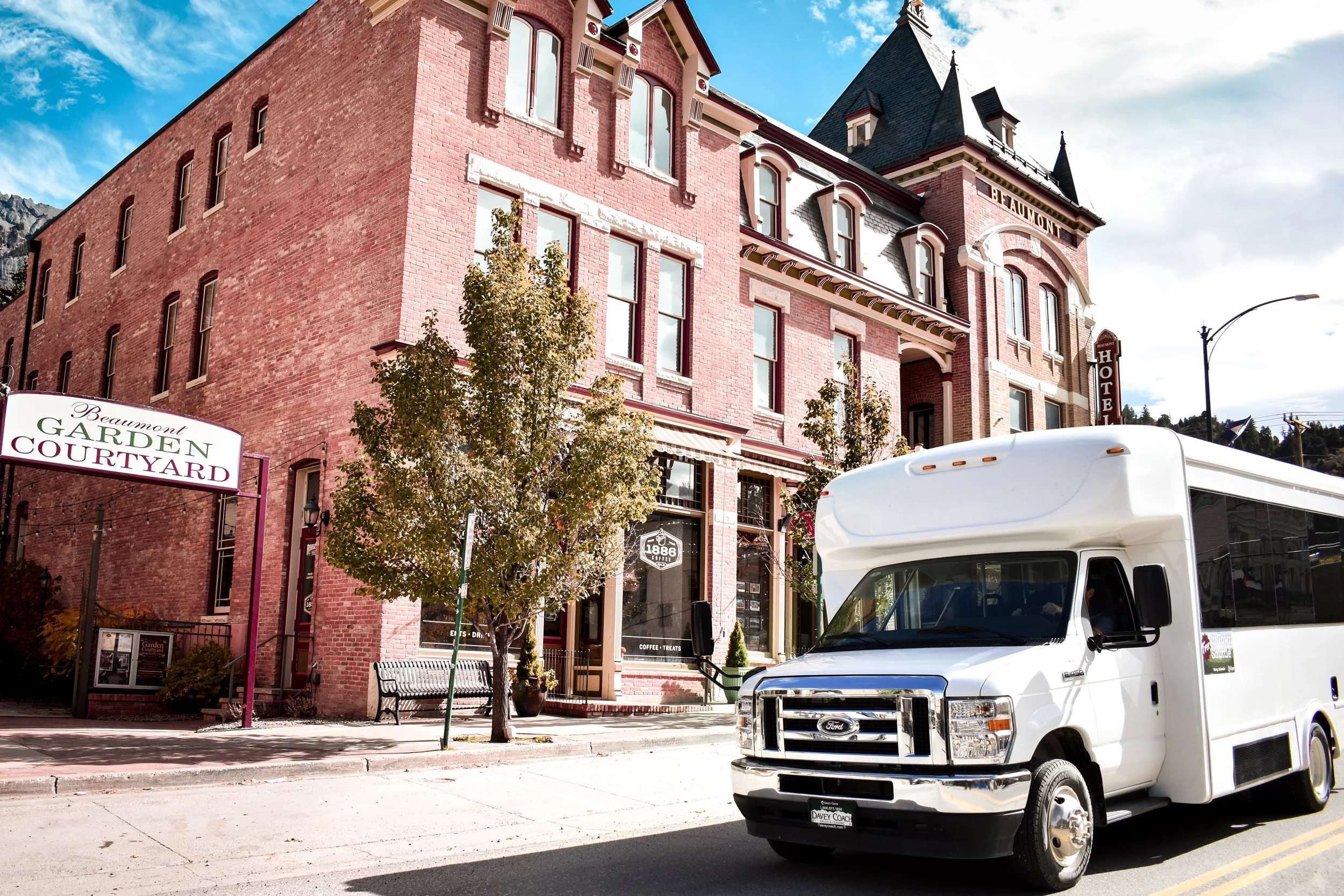 White shuttle bus infront of brick buildings