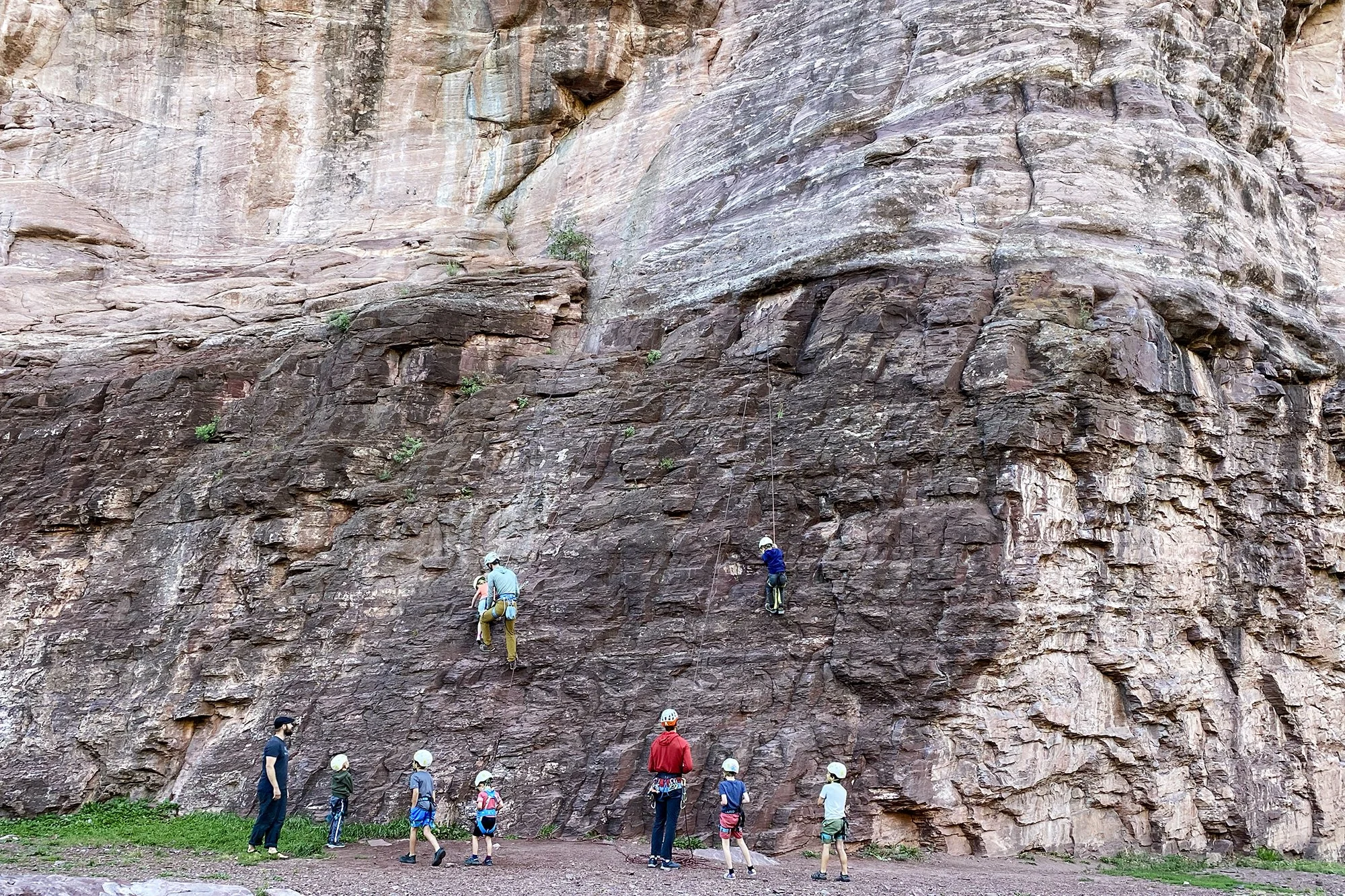 Guides teach children how to climb on a sandstone cliff.