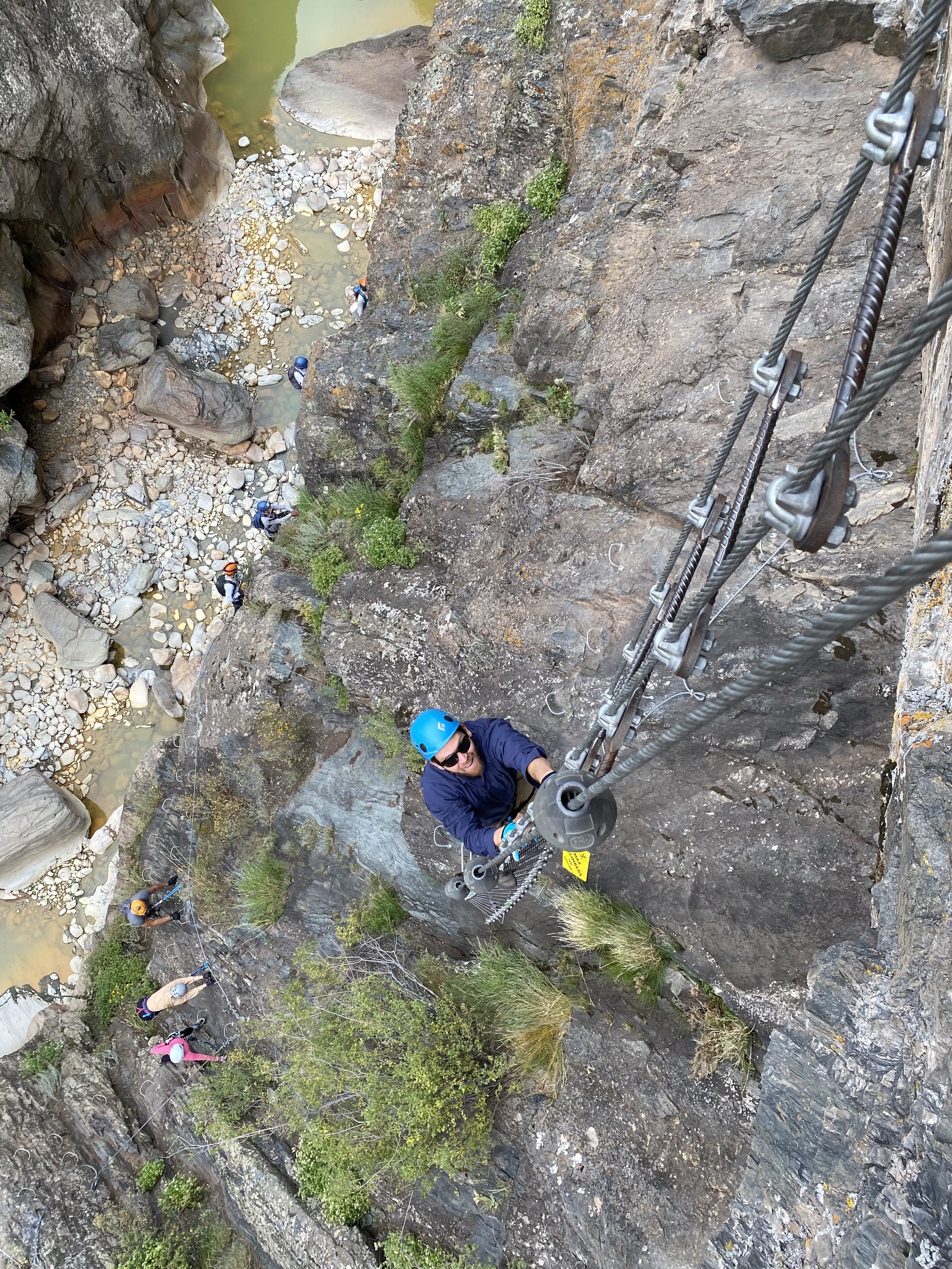 guy in blue helmet and shirt climbing the helix ladder pon upstream via ferrata