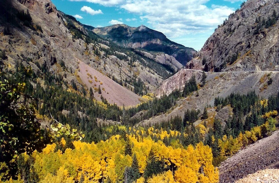 Scenic view of colorful autumn aspens and rugged canyon walls in the Uncompahgre Gorge along the San Juan Skyway in Colorado.