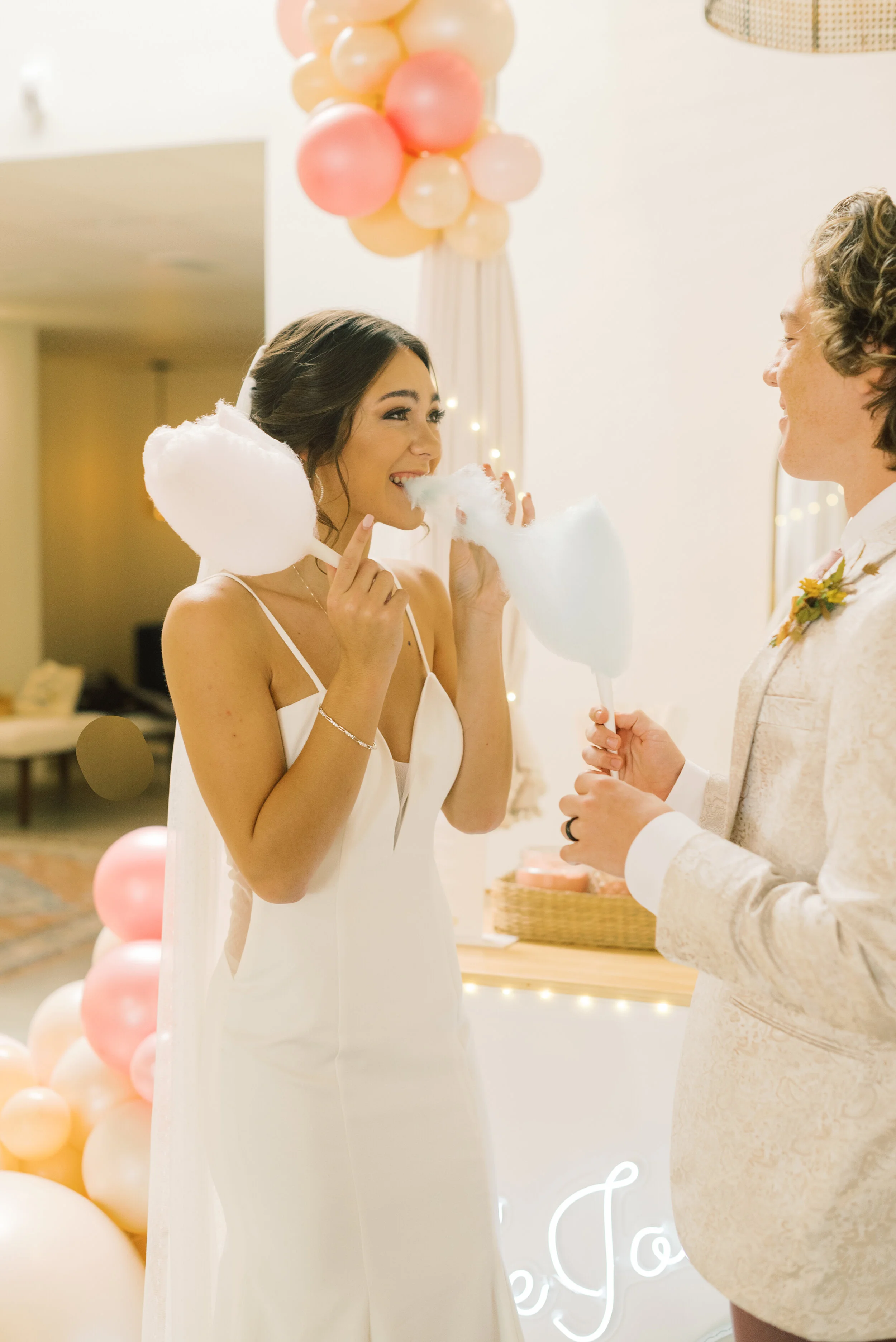 A bride holds a snagged piece of The Jolly Sheep cotton candy is smiling with joy and anticipation at her groom.