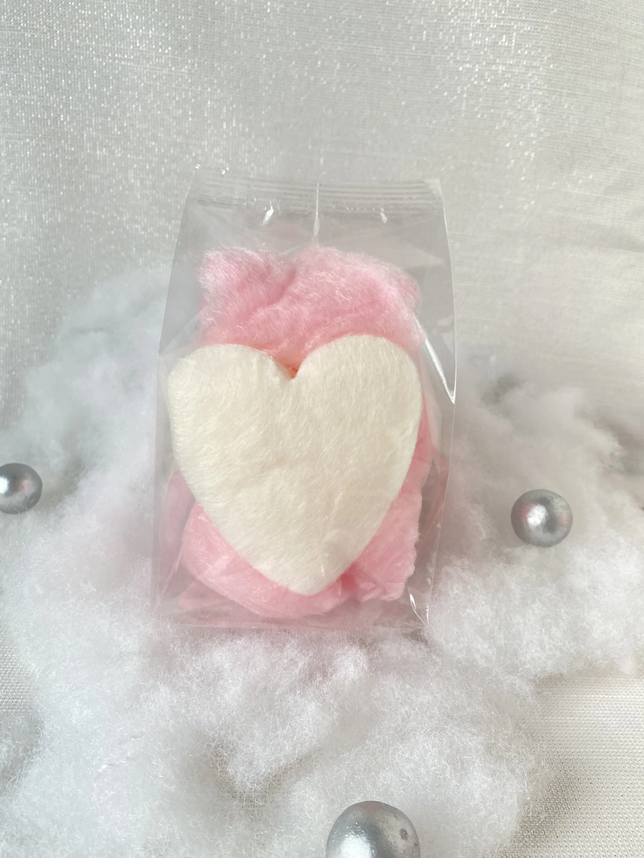 a Heart shaped cotton candy favors in pink and white on a styled backdrop