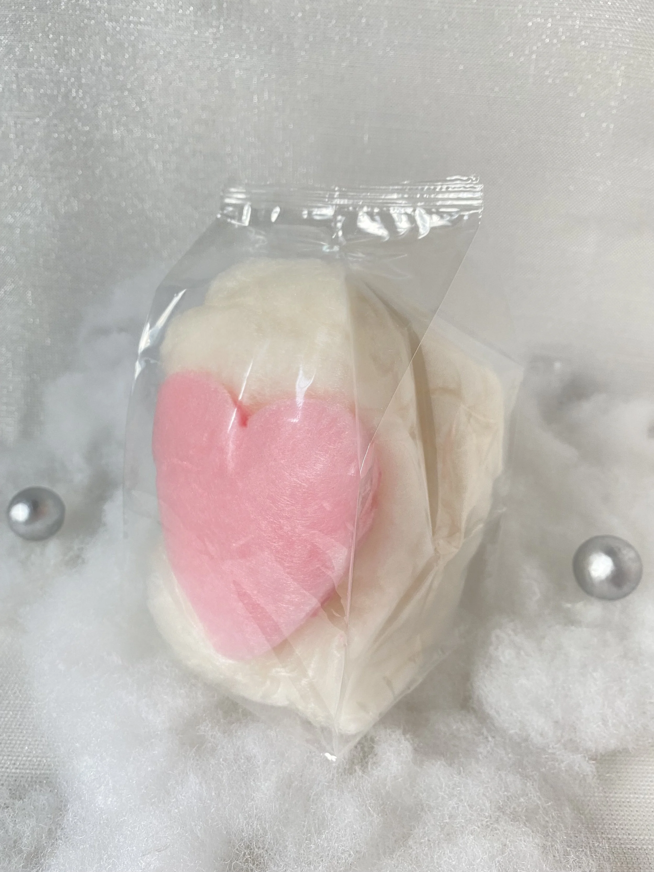 a Heart shaped cotton candy favors in pink and white on a styled backdrop