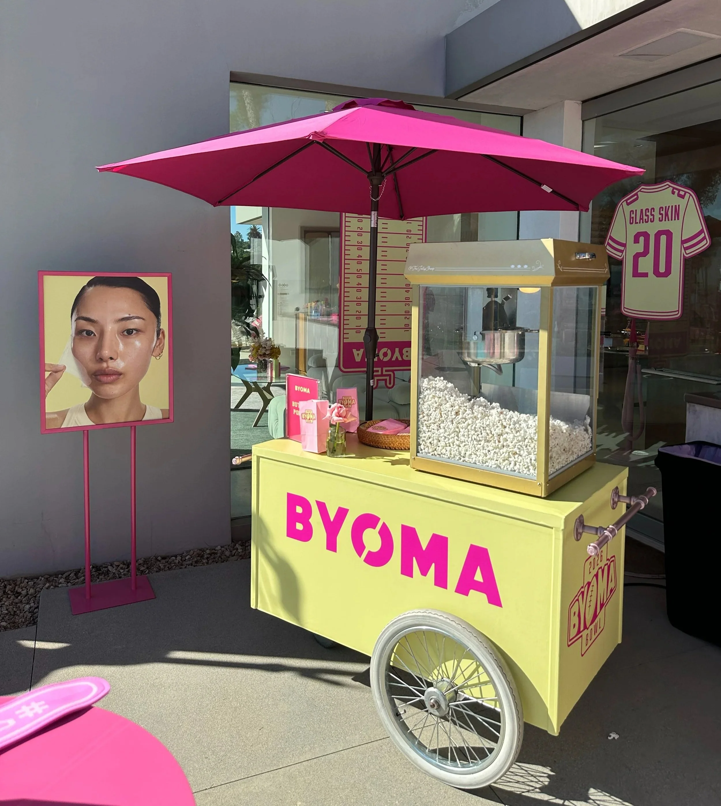 a fully customized popcorn cart with the brand name BYOMA on the front and a matching umbrella