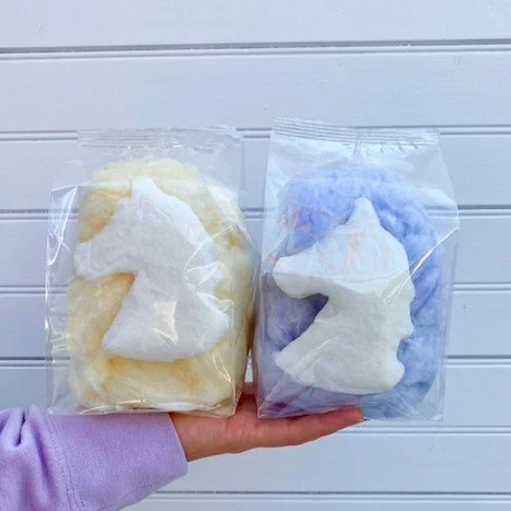 a hand holding up two unicorn cotton candy favor bags