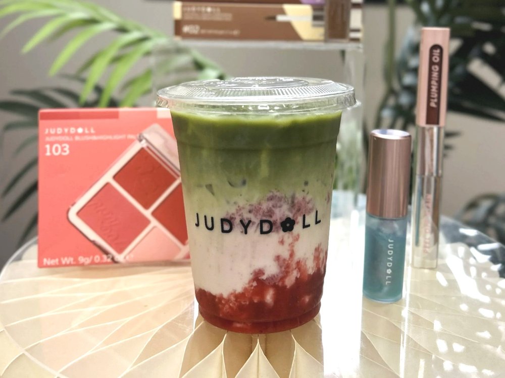 A custom clear cup for a JUDYDOLL activation with matcha latte inside.