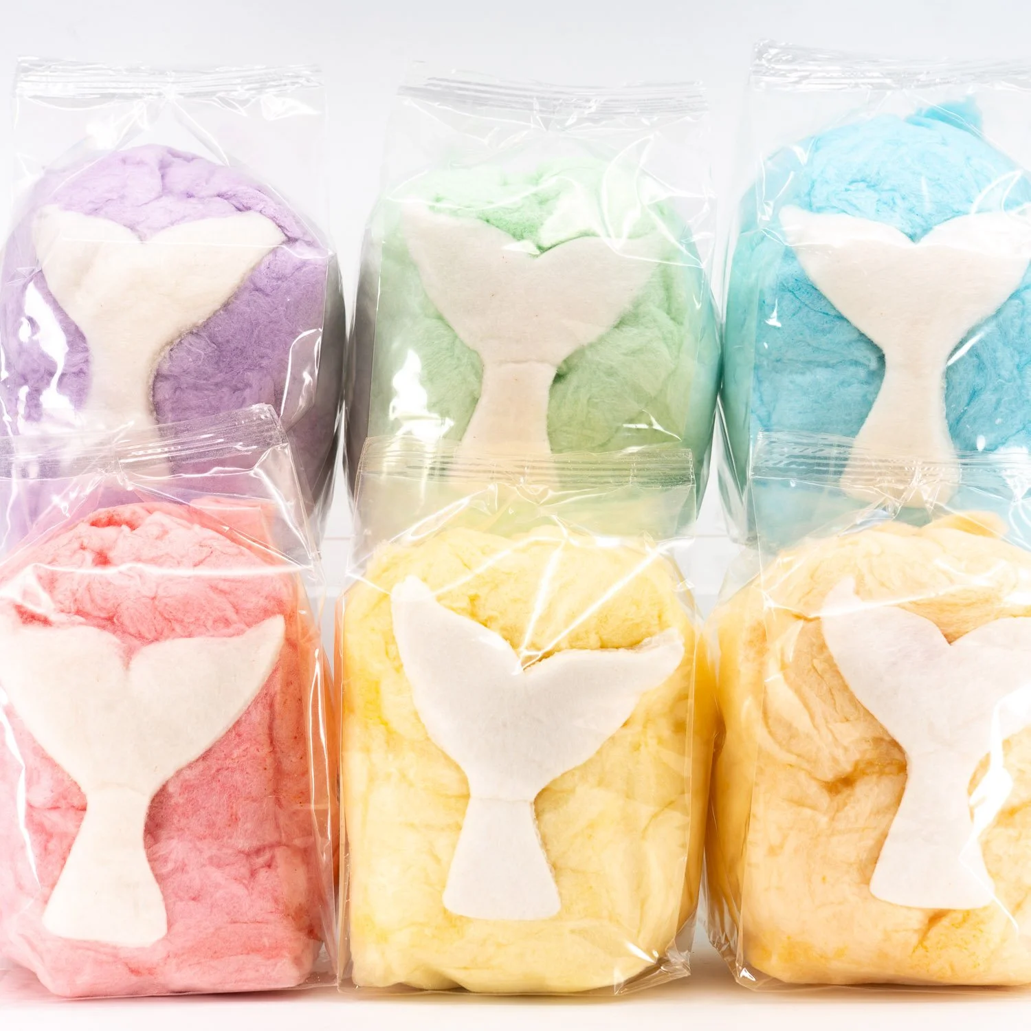a collection of different color cotton candy favor bags with edible mermaid tails in each