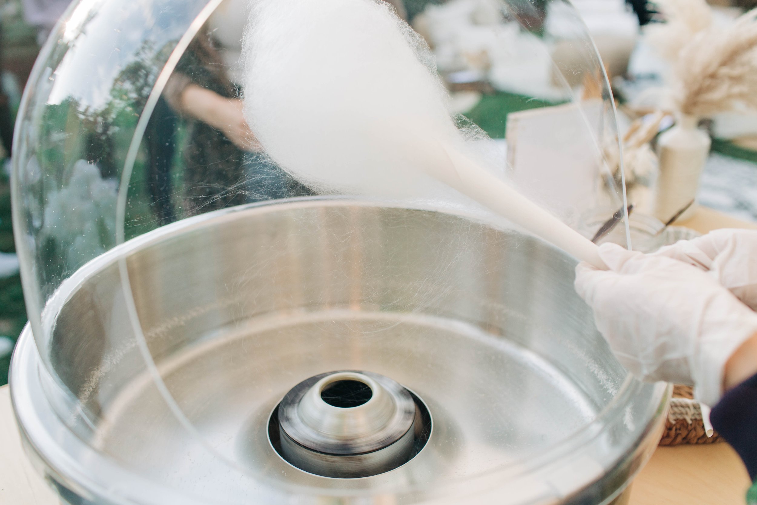 white cotton candy being spun onto a cone above a cotton candy machine