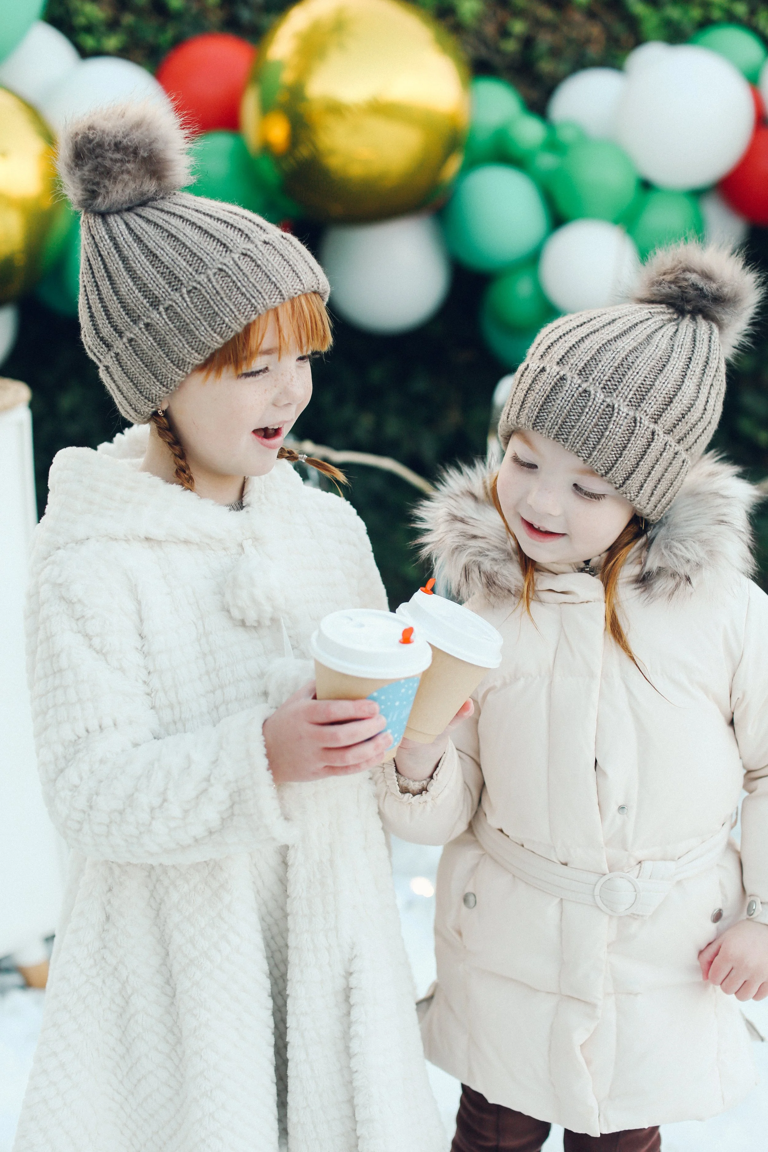 two children smiling and looking at their hot chocolate cups