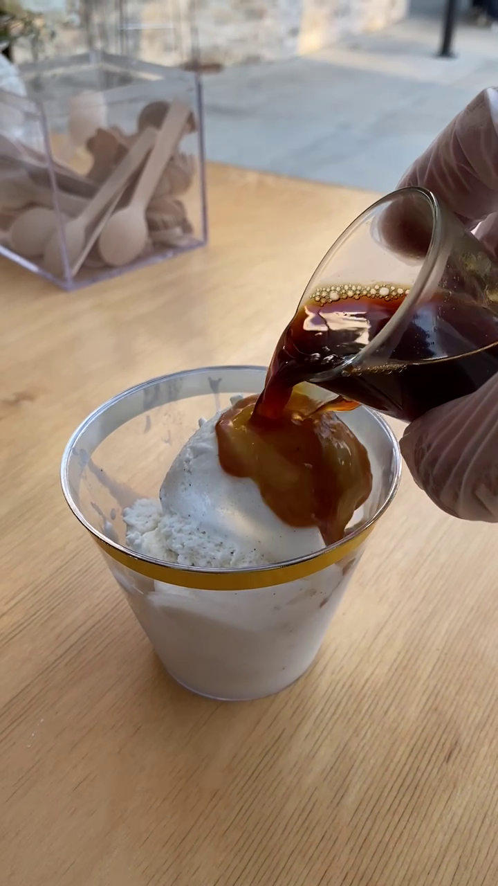 Espresso being poured over a scoop of gelato inside a gold accented cup