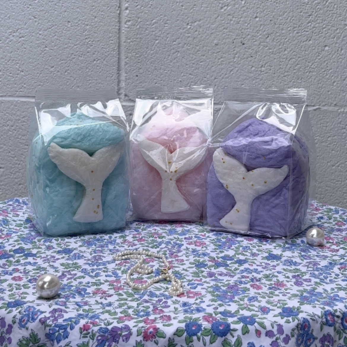 mermaid tail cotton candy favor bags set on a shimmering table with undersea vibes
