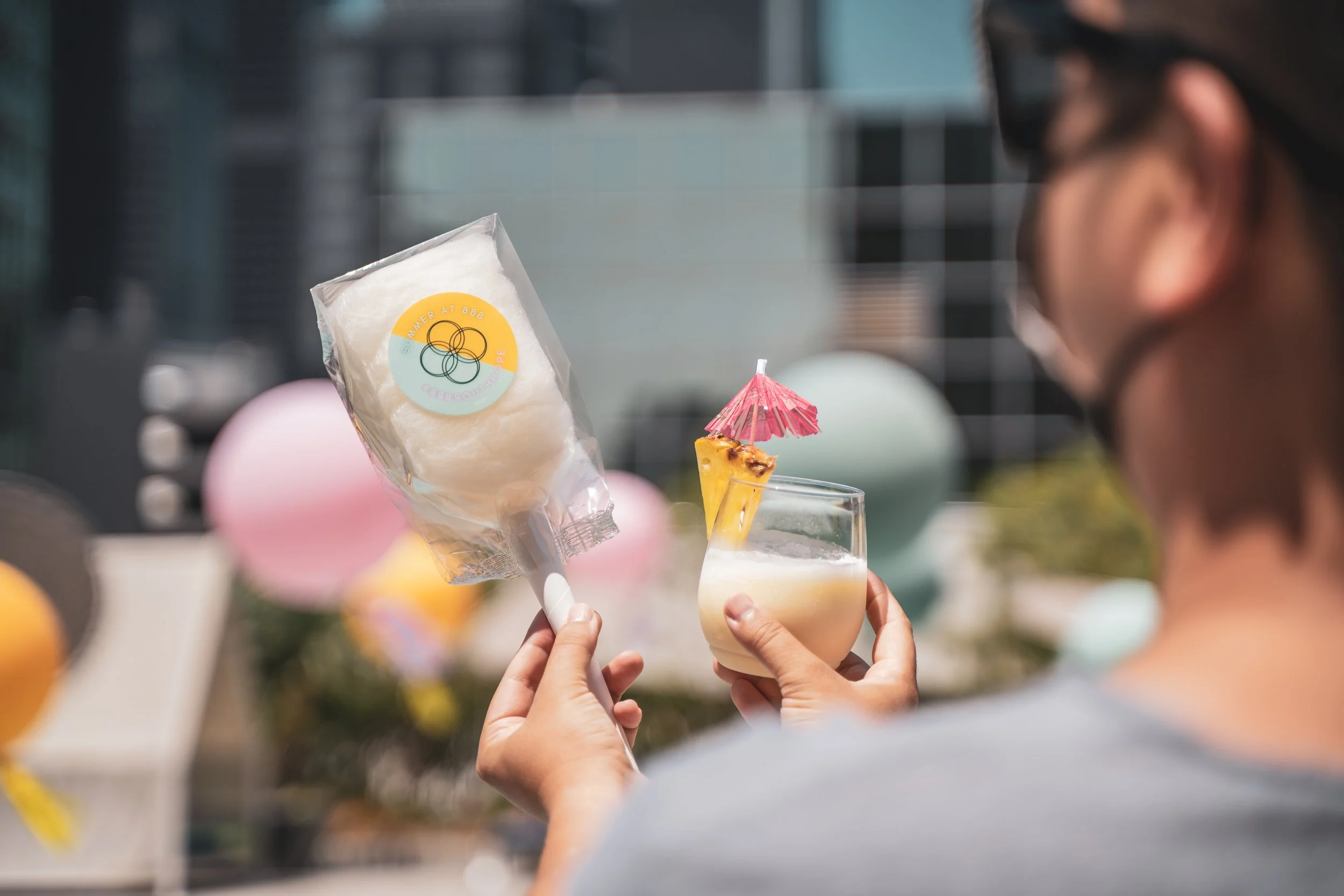 a custom packaged cotton candy favor and a slushie held up by two hands