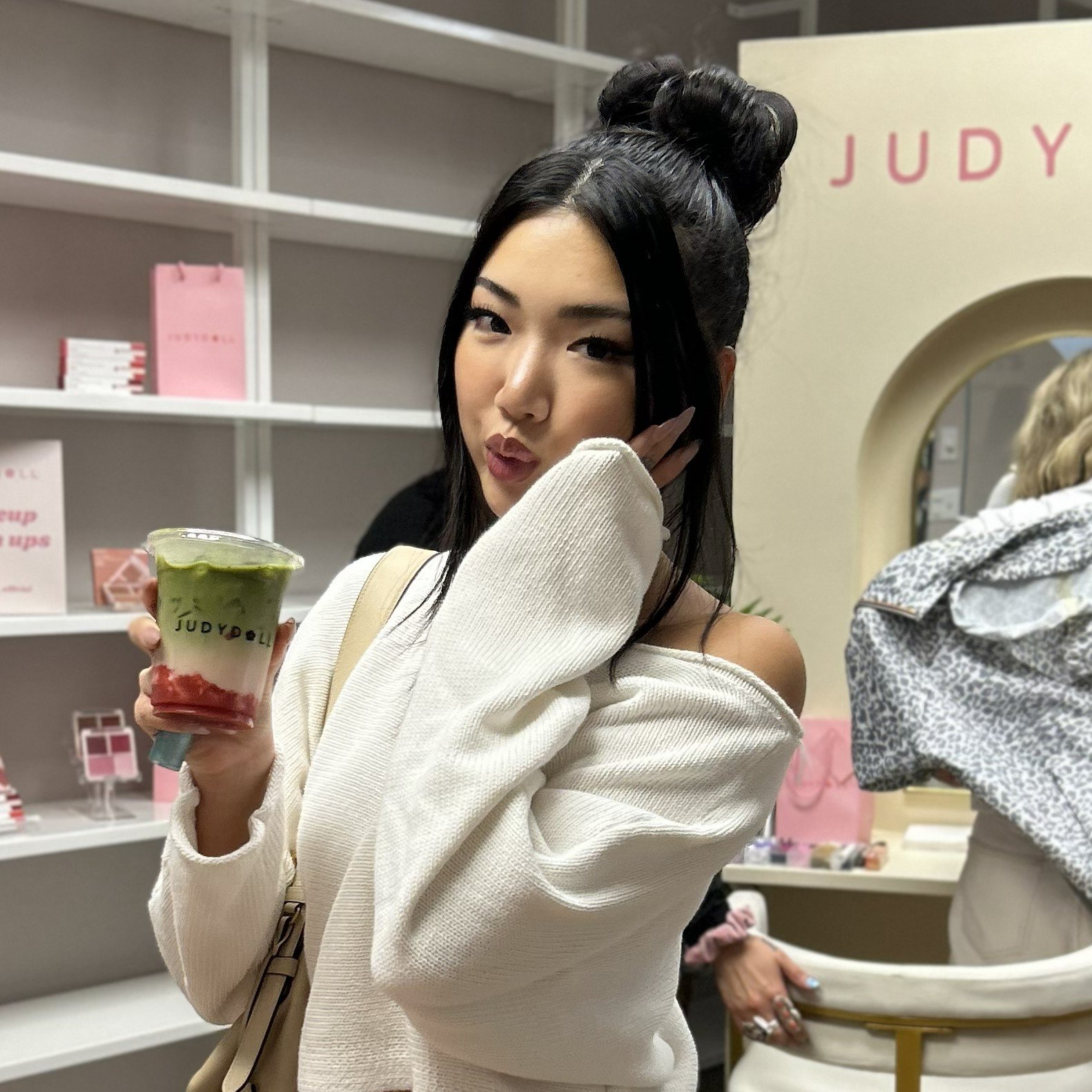 a woman holding a matcha cup with a custom JUDYDOLL logo at a PR event