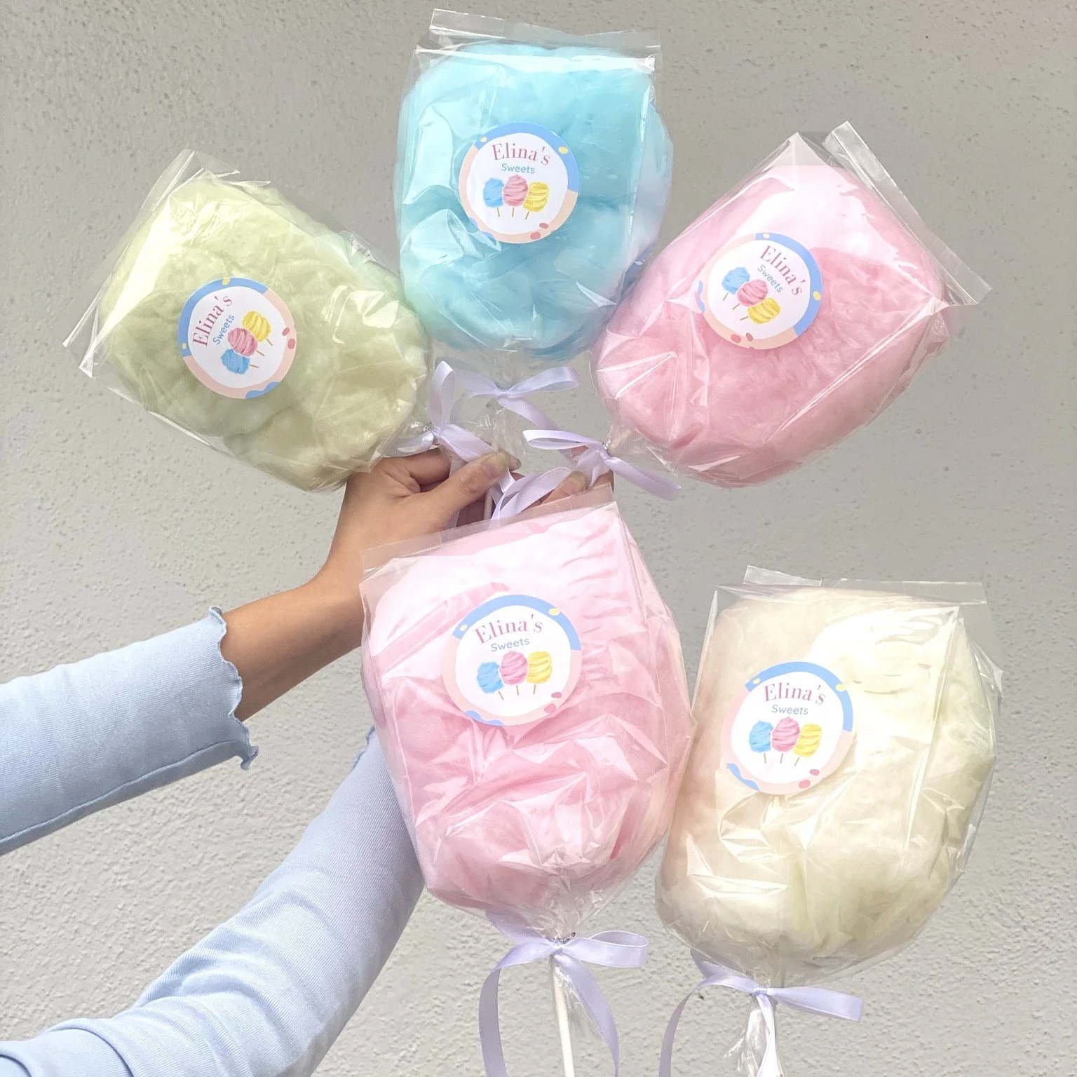 an assortment of pastel cotton candies on a stick