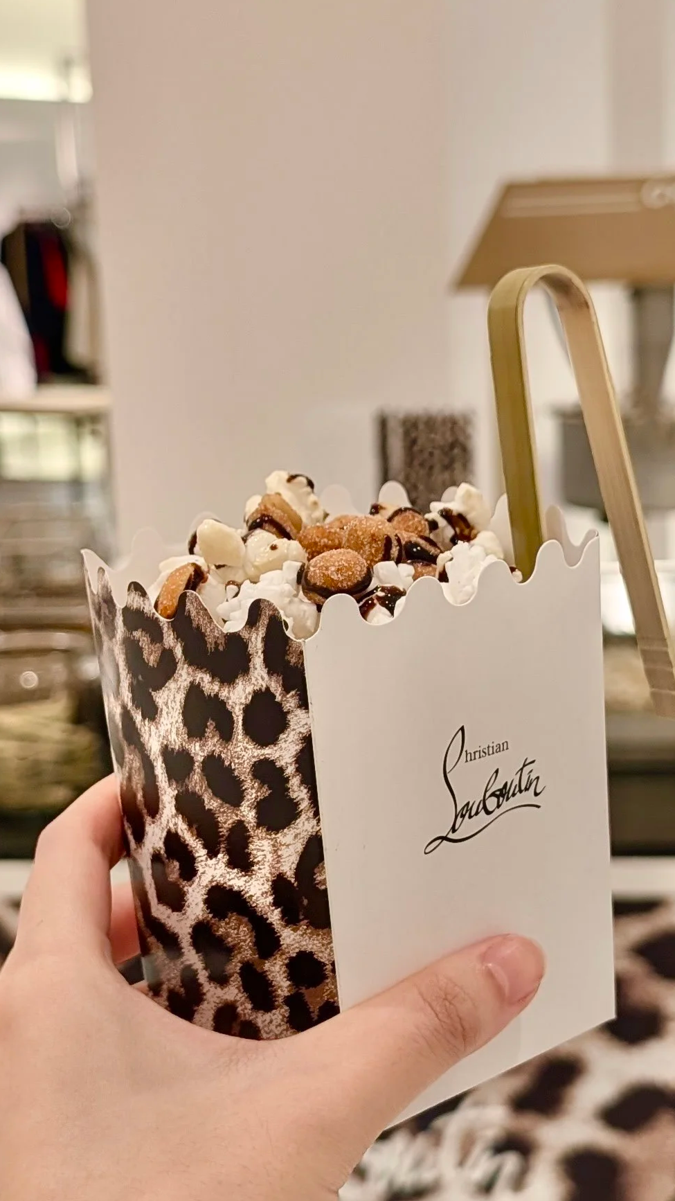 A fully customized Christian Louboutin popcorn box with mini tongs and popcorn drizzled with chocolate and toppings for an experiential marketing pop-up