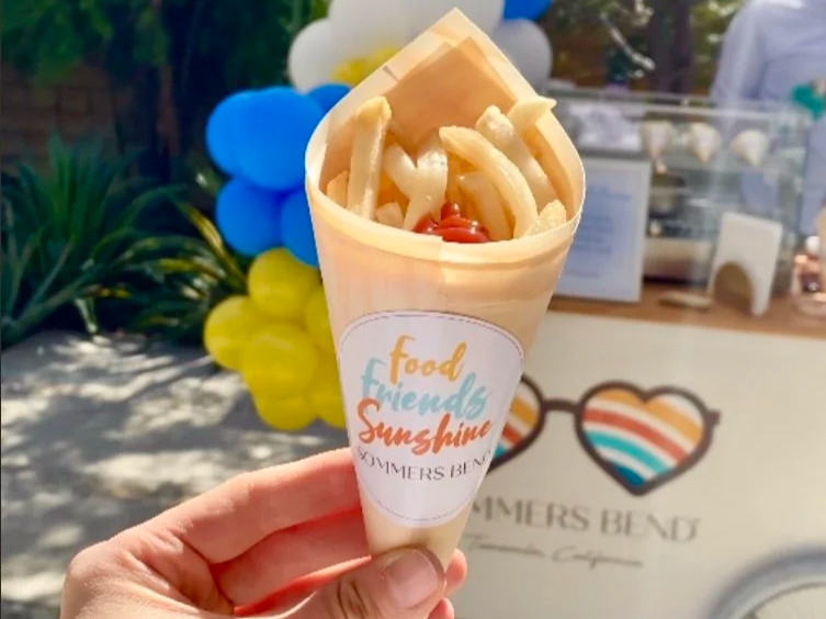 French fries in a bamboo cone, with a french fry cart station behind.