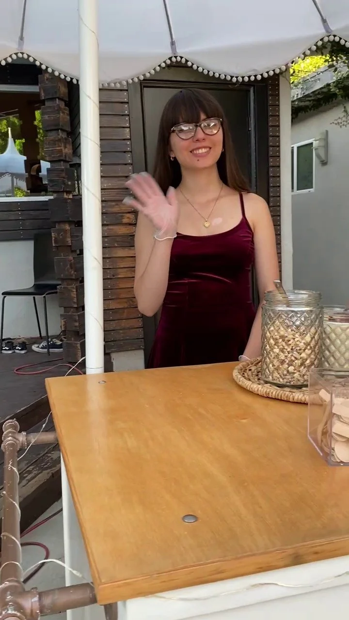 A gelato cart attendant waving and smiling