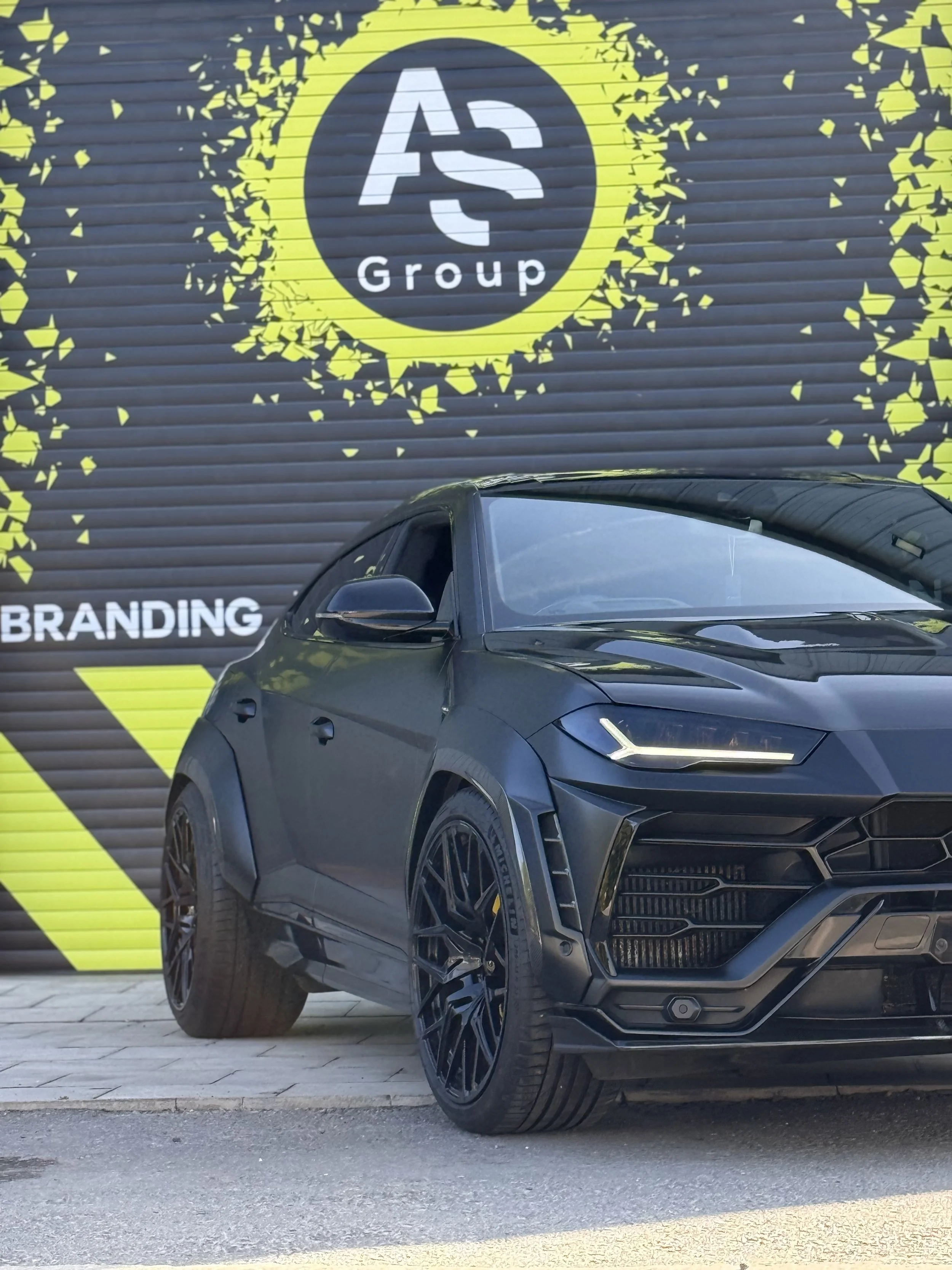 Lamborghini Urus in a satin black wrap in front of an Auto-Skins shutter.
