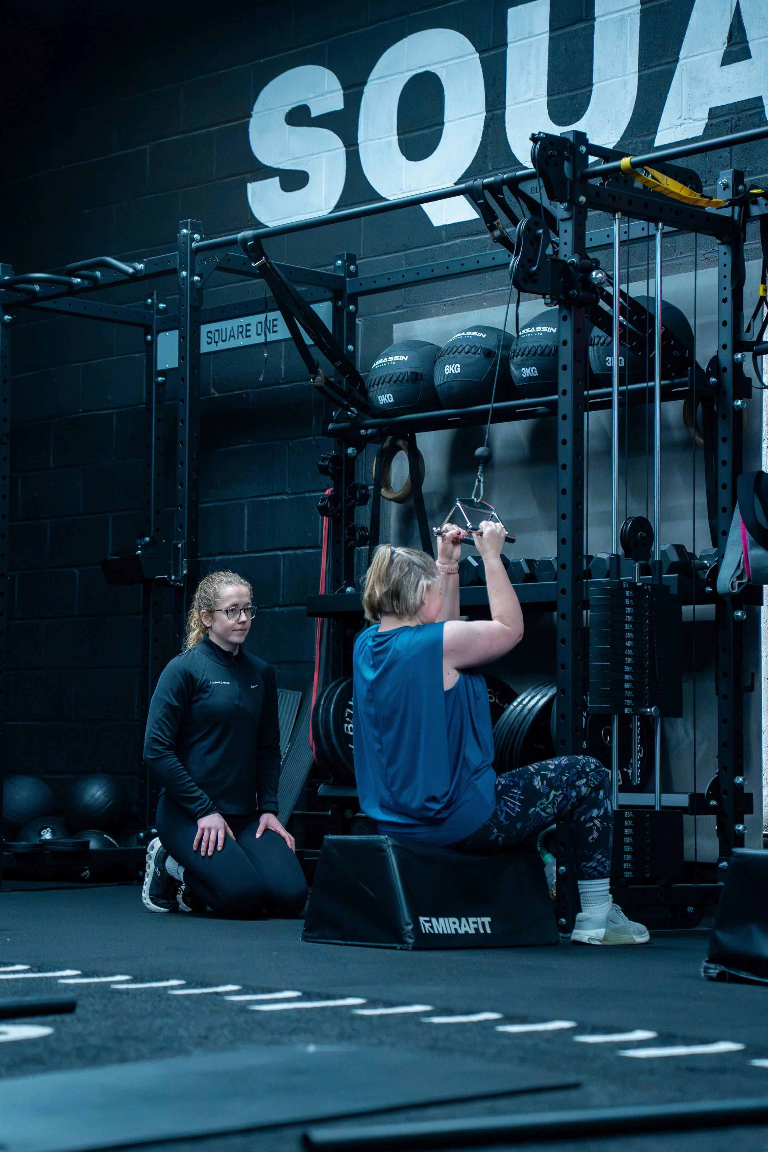 Coach helping a member’s technique during a strength training session at Square One personal training gym in Wimborne.
